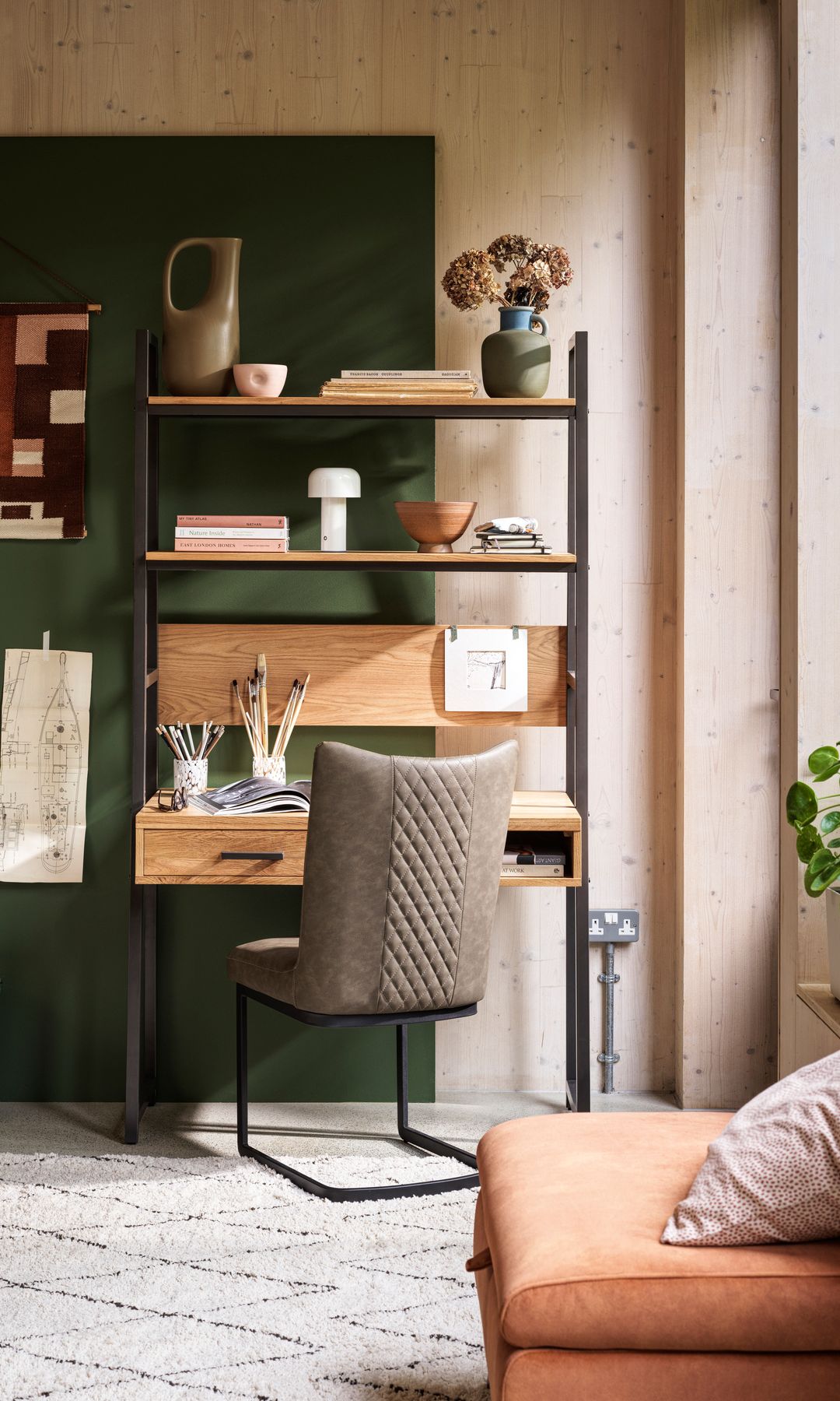 Despacho con mueble que incluye mesa y estantería, silla de cuero, panel vertical verde, alfombra y pared de madera