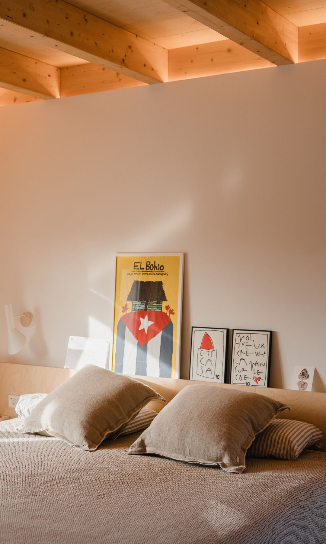 Dormitorio con vigas de madera, cabecero de madera con balda, ropa de cama en colores tierra suave 