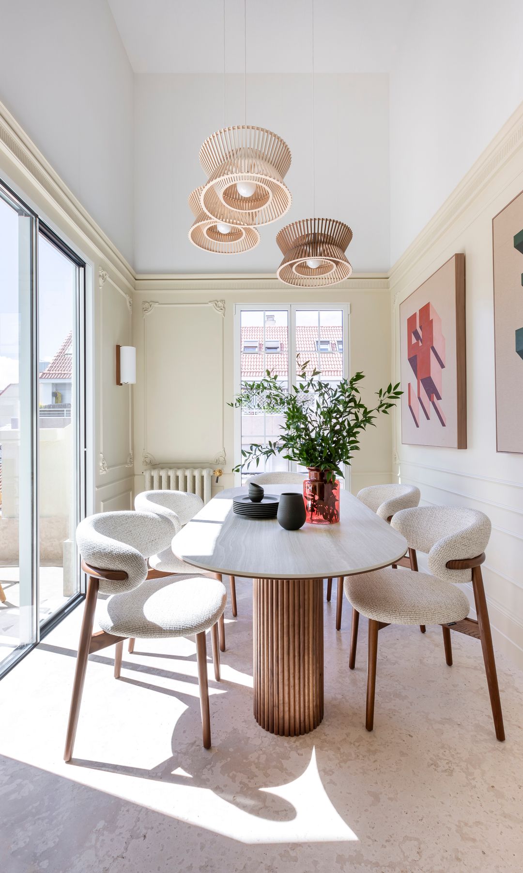 Comedor con salida a la terraza, sillas tapizadas, mesa de madera, lámparas de techo y cuadros