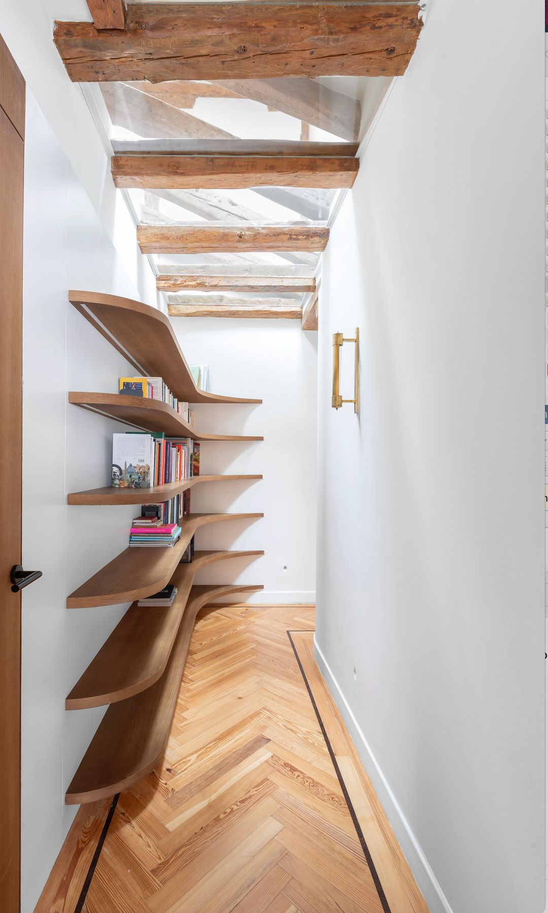 Pasillo estrecho con baldas de madera curvas formando una estantería 