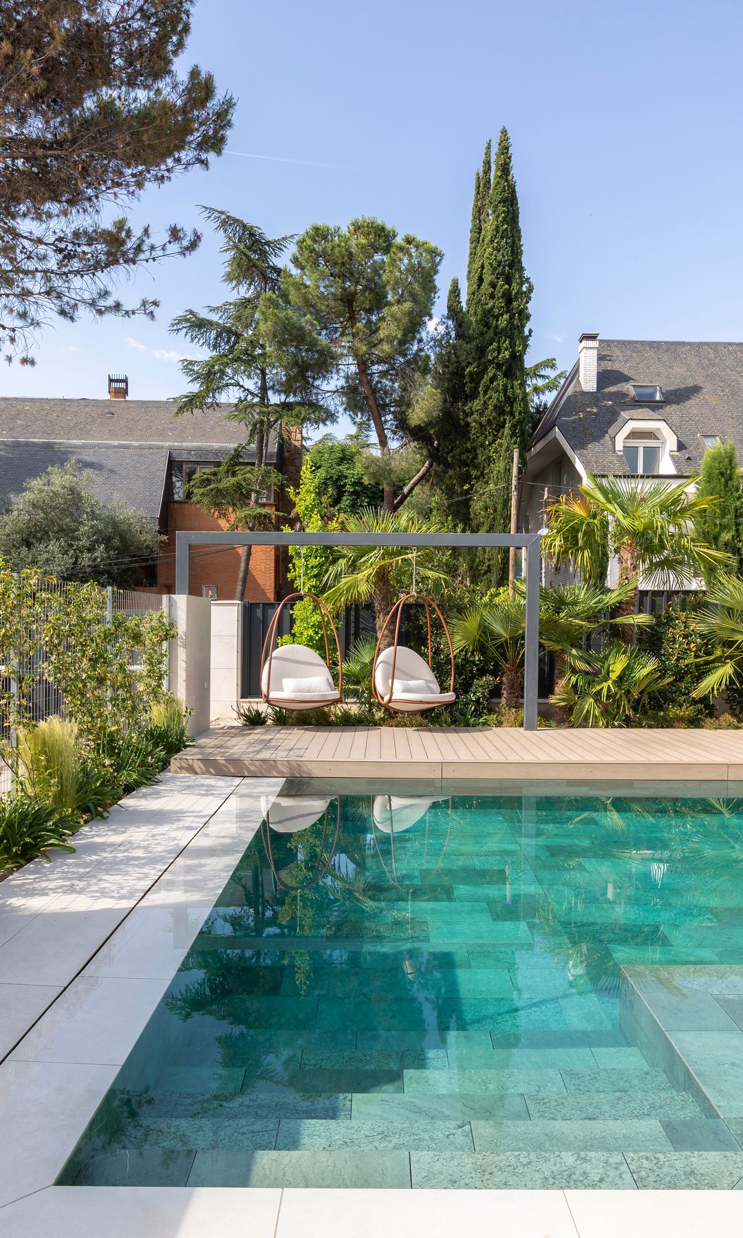 Exterior con piscina y sillones colgantes, en un proyecto de arquitectura de Consuelo López Pérez y Fernando de Mier Domínguez, con interiorismo de Emmme Interiorismo y paisajismo de Emmme y Verónica Erasmo Zago. Construcción de Luman Edificación y Restauración.