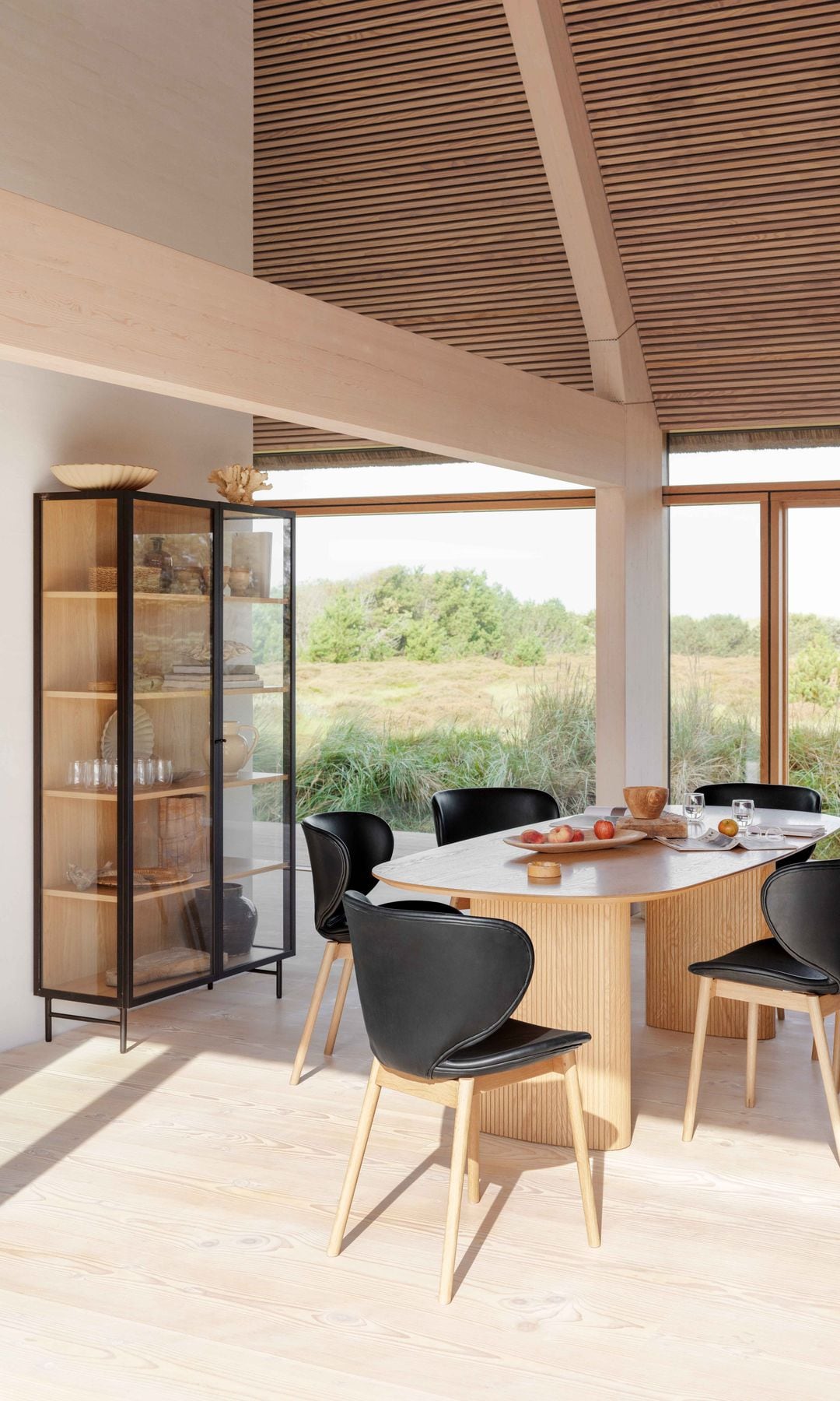 Comedor con mesa de madera, sillas negras, vitrina con el marco negro y XL, techo de madera