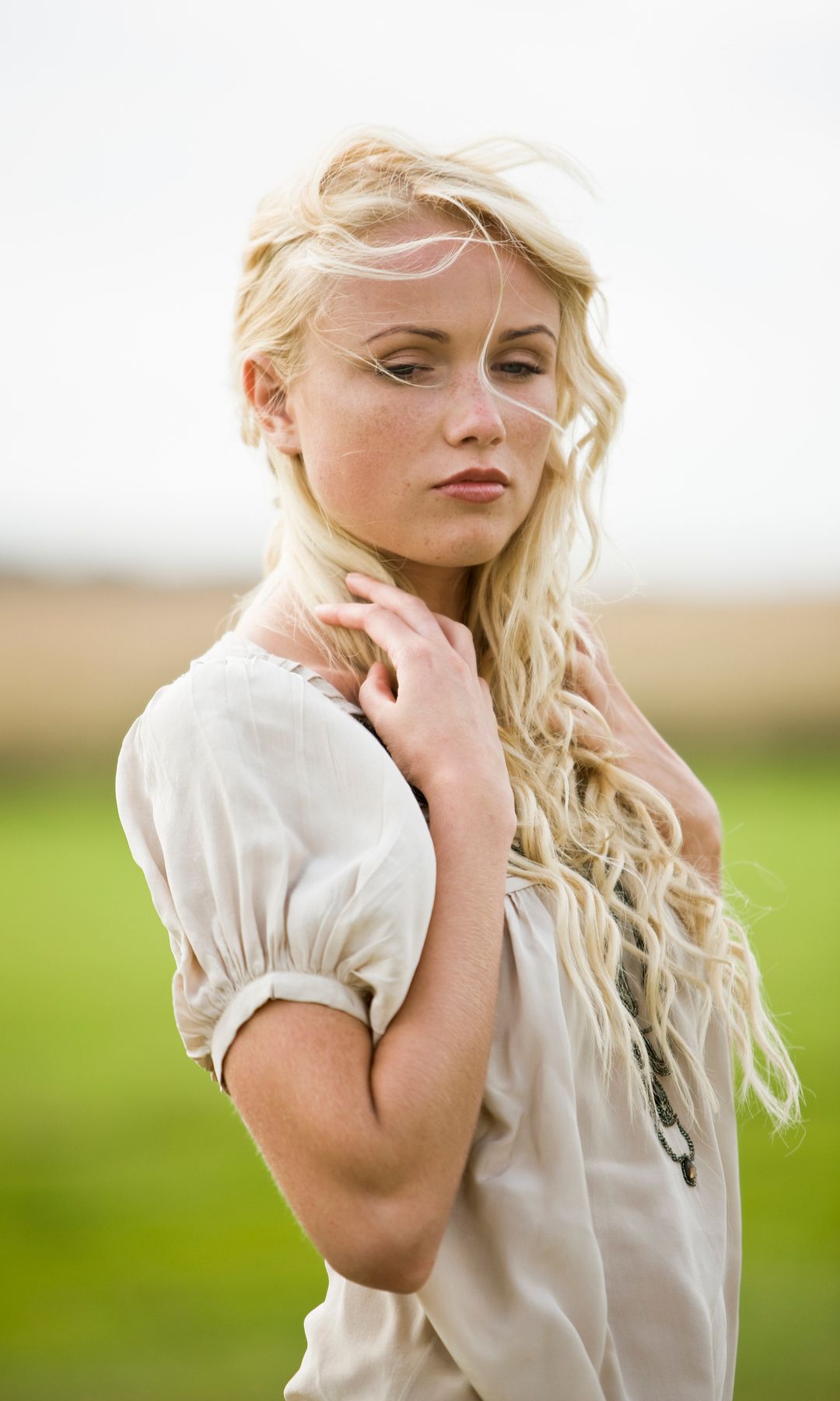 Mujer rubia pelo largo seria en el campo