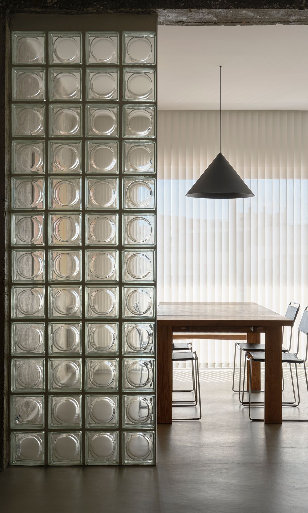 Comedor con tabique de pavés, mesa de comedor de madera, lámpara de techo 