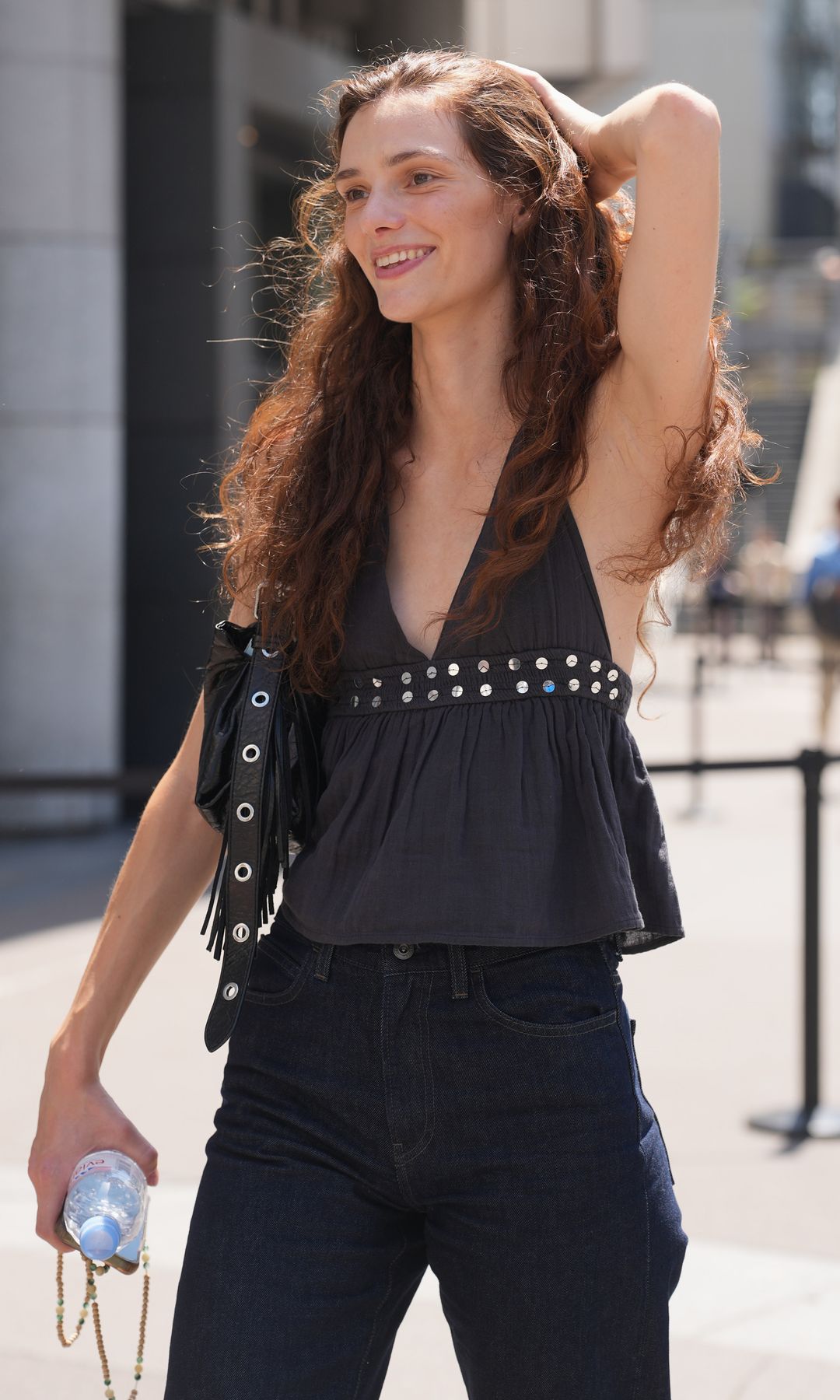 PARIS, FRANCE - JUNE 24: A guest wears long wavy brown hair, a black sleeveless top with waist nails details, black wide-leg jeans, a black shoulder bag, outside Lemaire, during Paris Fashion Week - Menswear Spring/Summer 2027, on June 24, 2026 in Paris, France