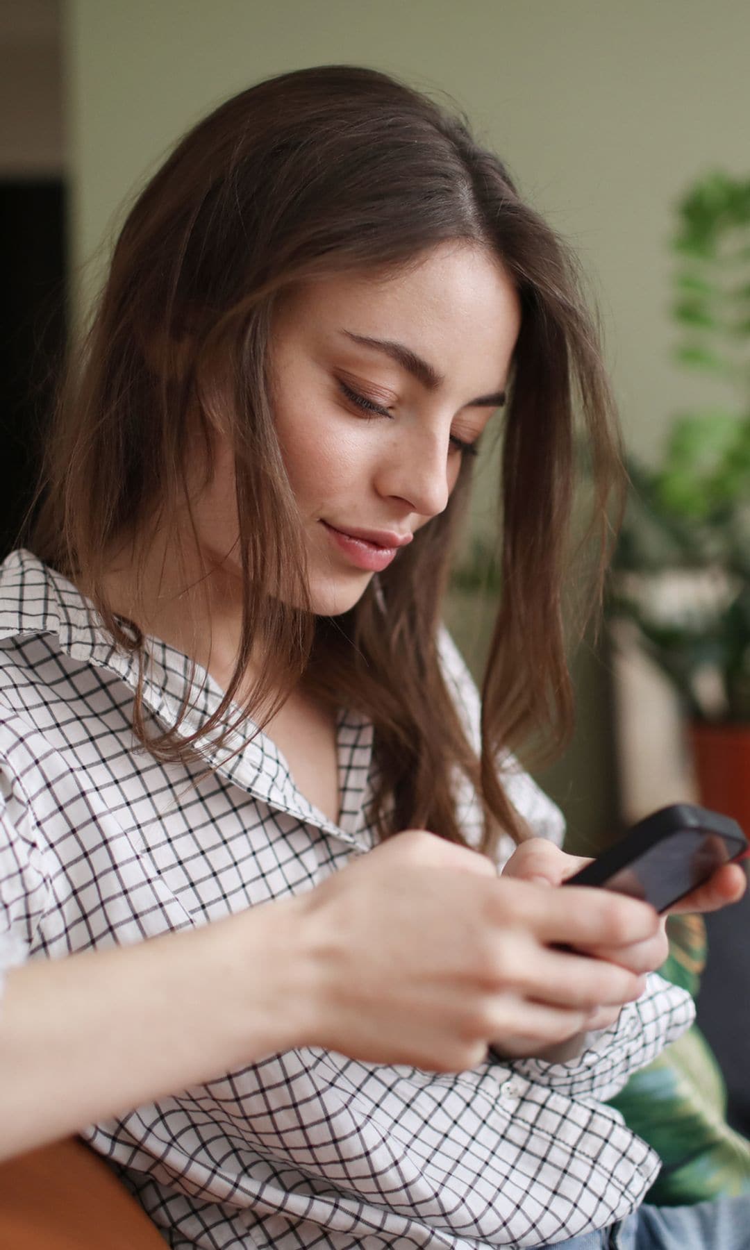 mujer mirando su teléfono móvil sentada en el sofá