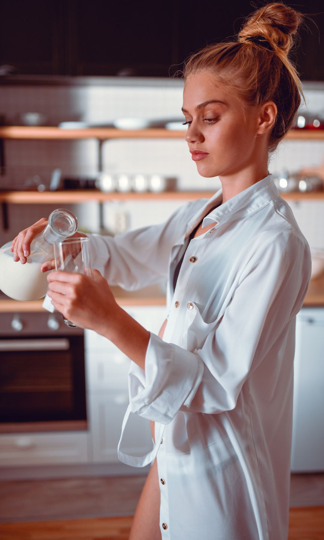 Mujer rubia poniéndose un baso de leche y kefir