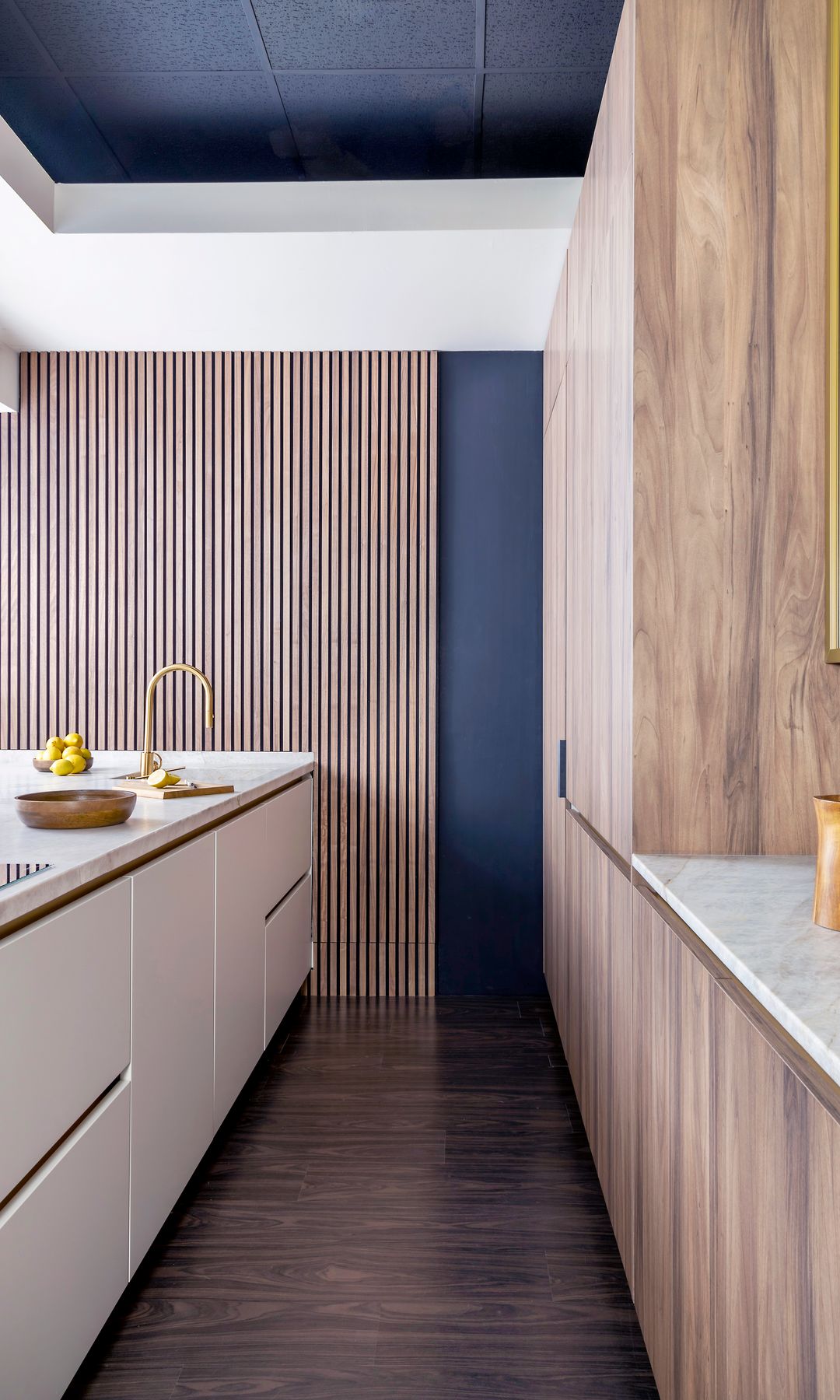Cocina con isla, electrodomésticos integrados, muebles de madera, isla blanca, grifería dorada 