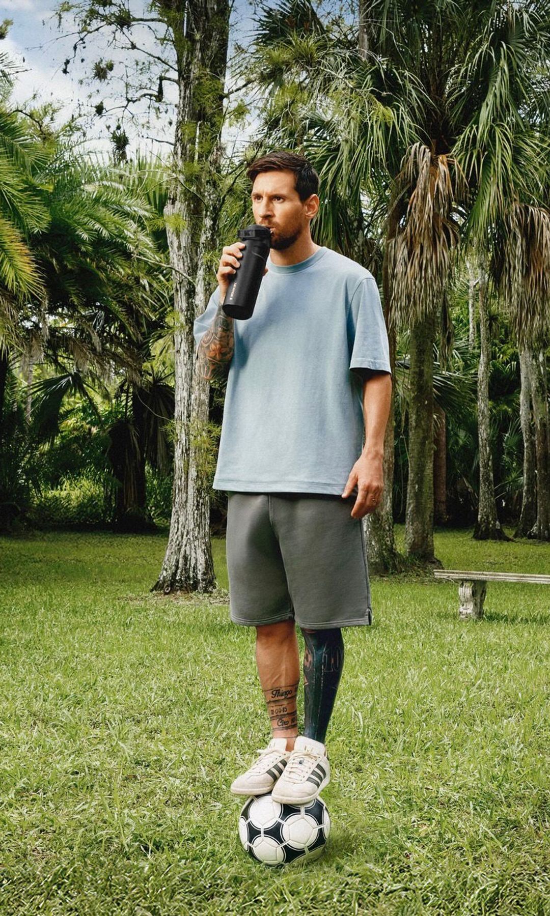 Leo Messi sobre un balón bebiendo agua