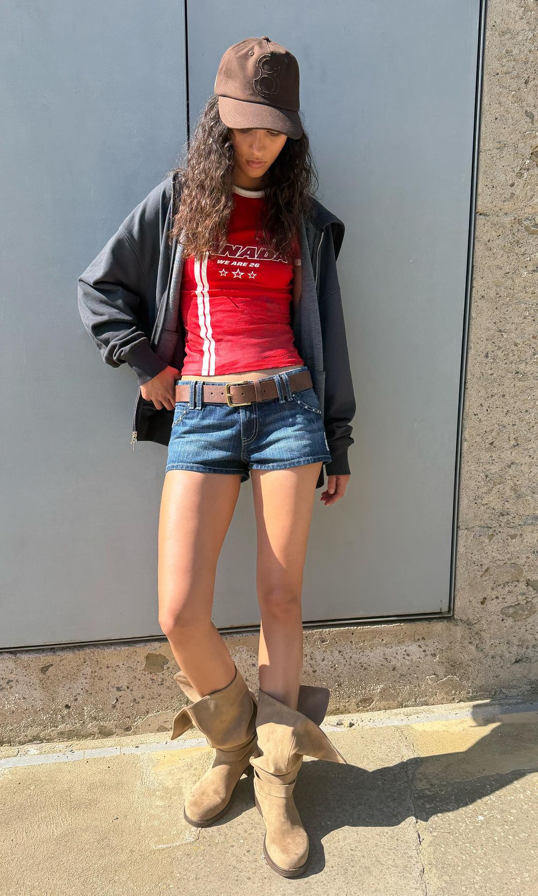 Look con camiseta de Canadá, shorts ultracortos y botas, de Bershka