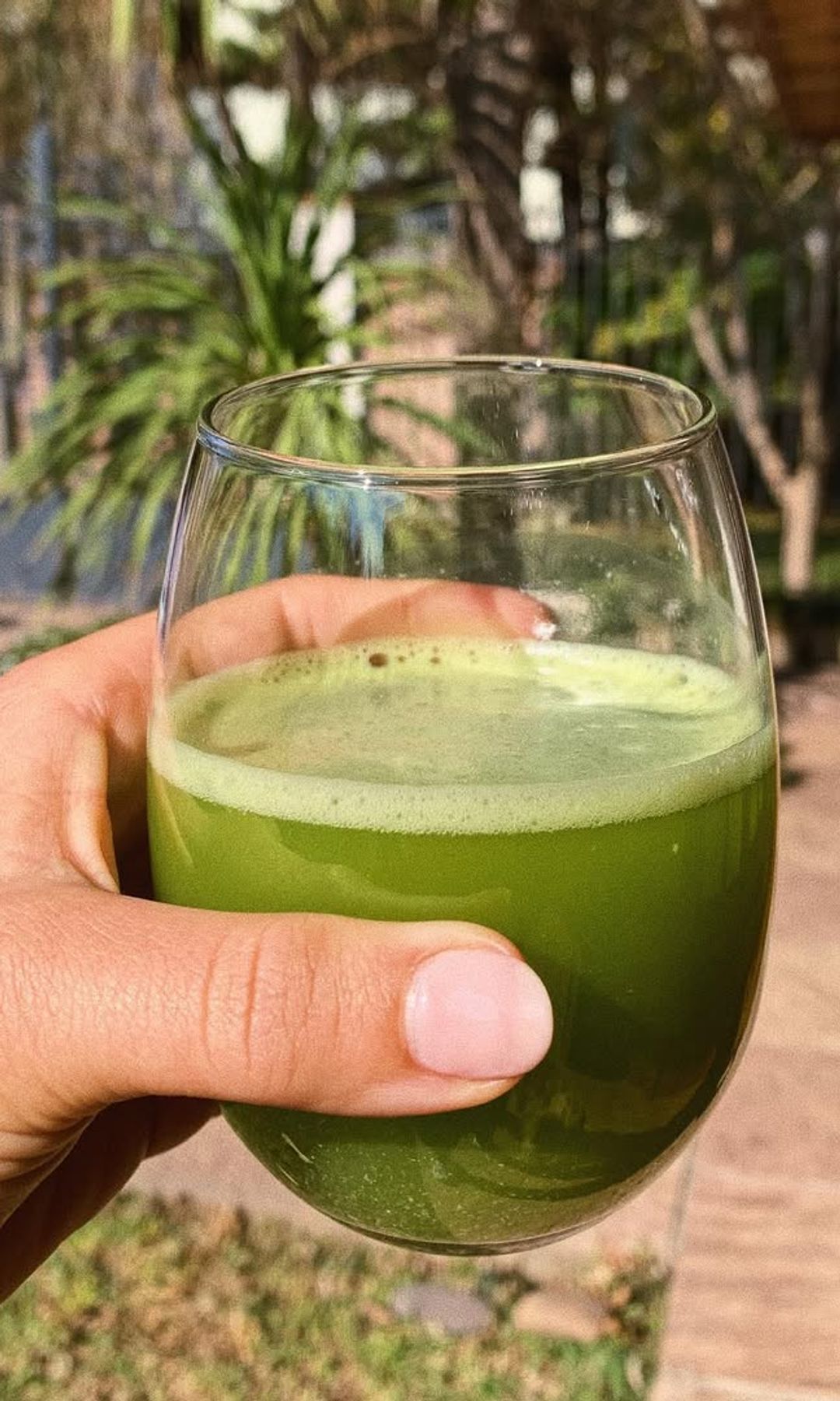 Vaso de zumo verde de apio sostenido en una terraza exterior