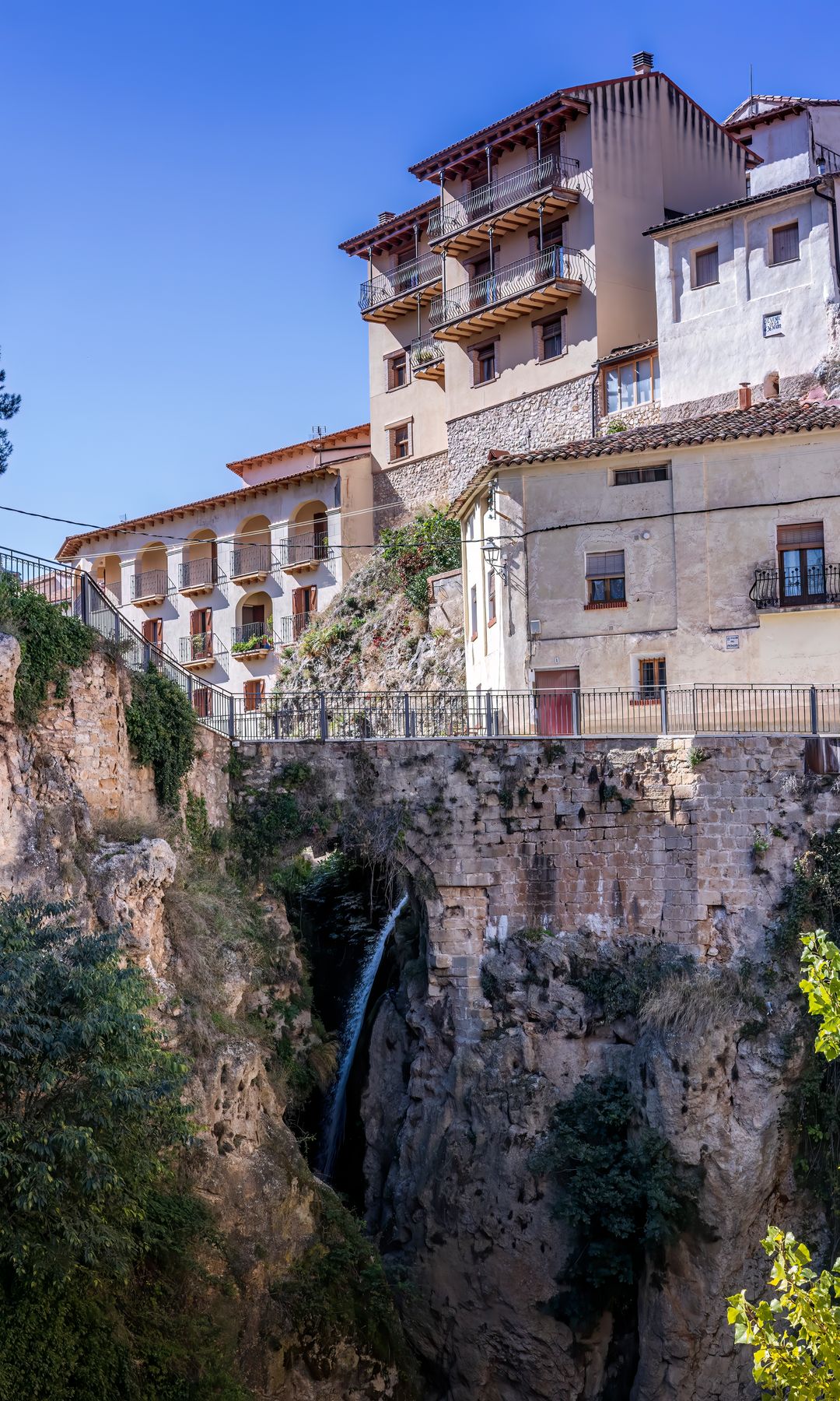 Cascada en el barranco de San Nicolás y casas tradicionales en el pueblo rural de Molinos, Maestrazgo, Teruel.