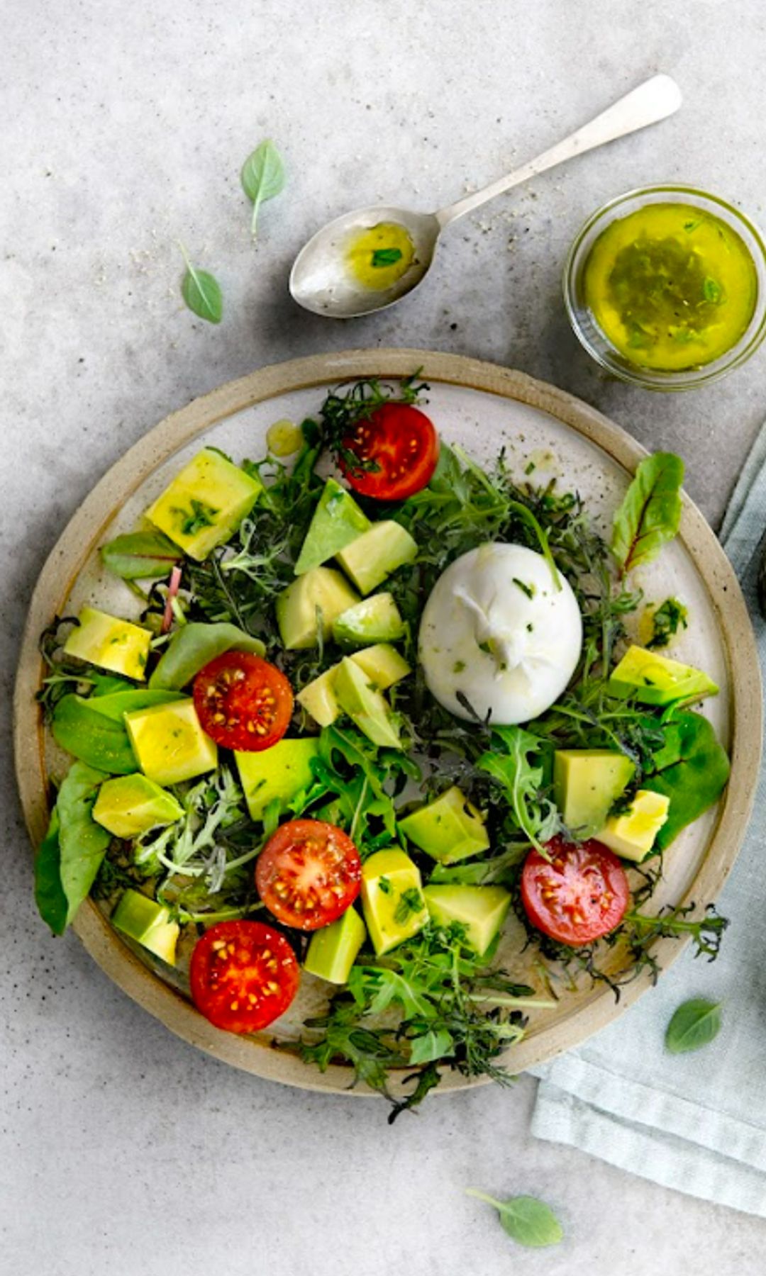 Ensalada de aguacate y tomate con huevo poché en plato redondo.