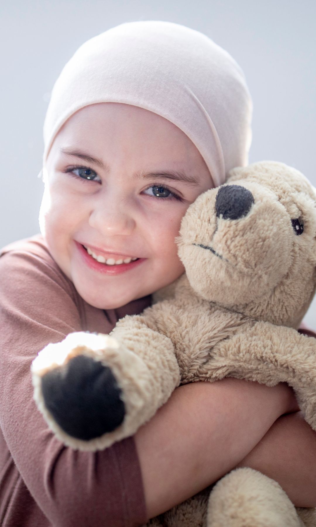 Niña con cáncer cogida de un osito de peluche