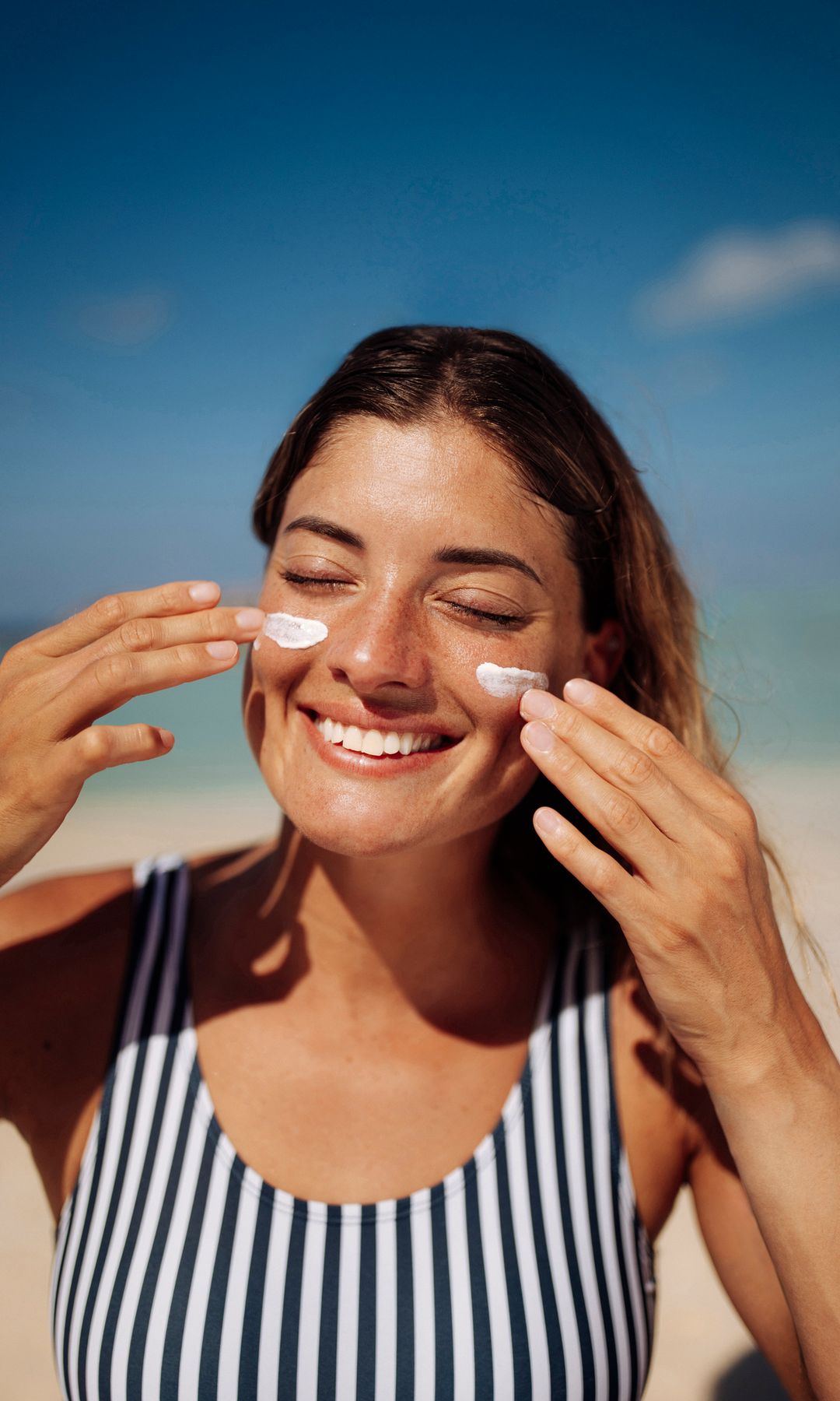 Una chica aplicándose protección solar en la cara