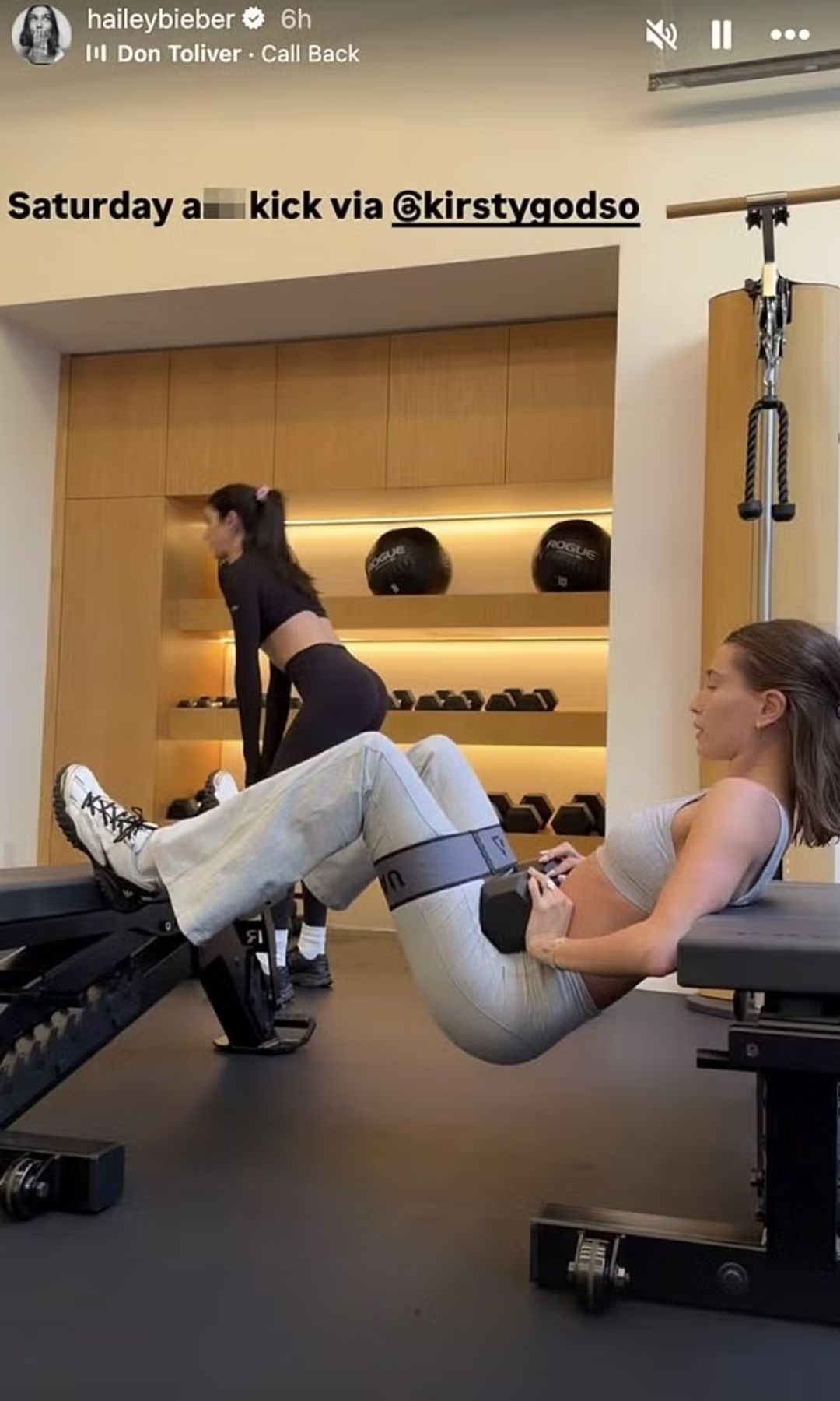 Hailey Bieber entrena glúteos con una mancuerna y una banda elástica entre dos bancos