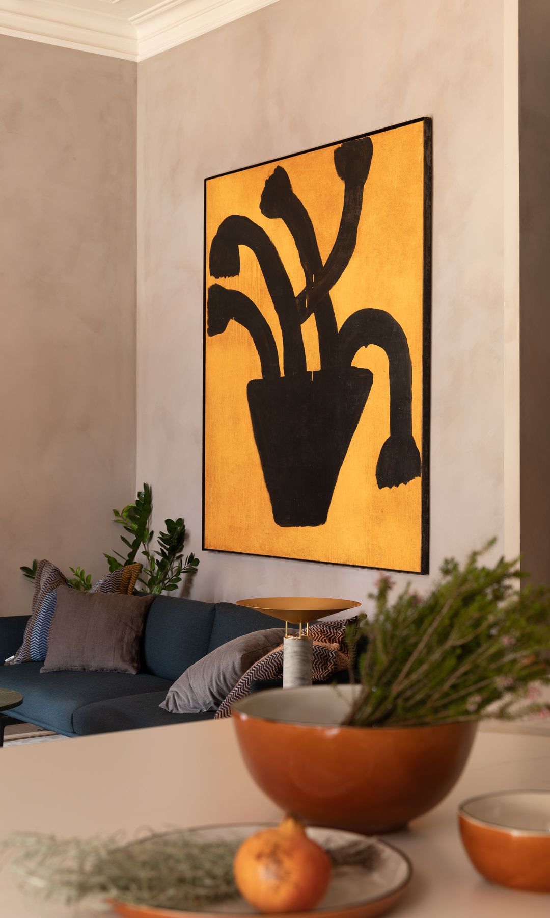 Cocina abierta al salón con cuadro en color amarillo y negro en la pared del sofá