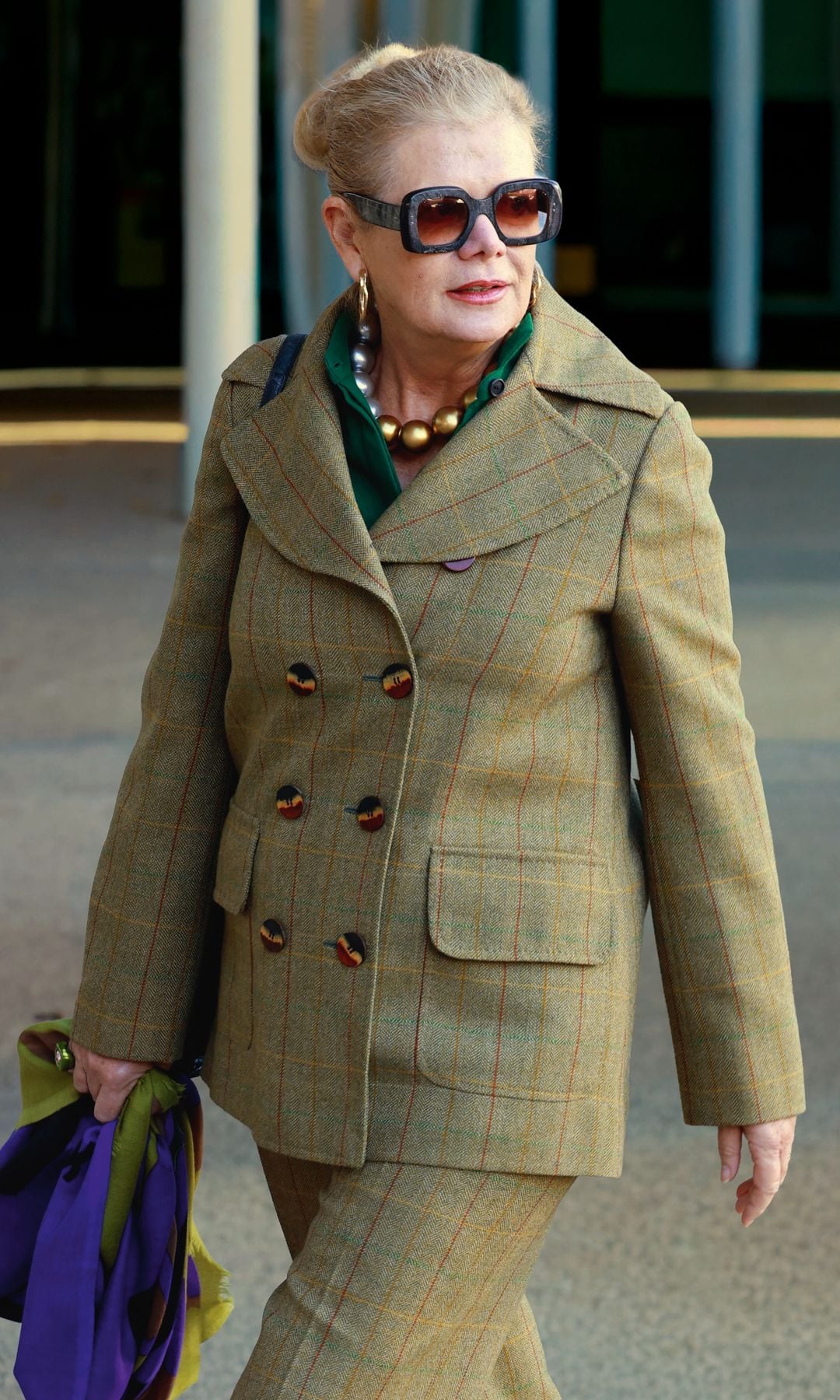 Lady Elena Foster camina con traje verde, gafas de sol grandes  y bolso morado.