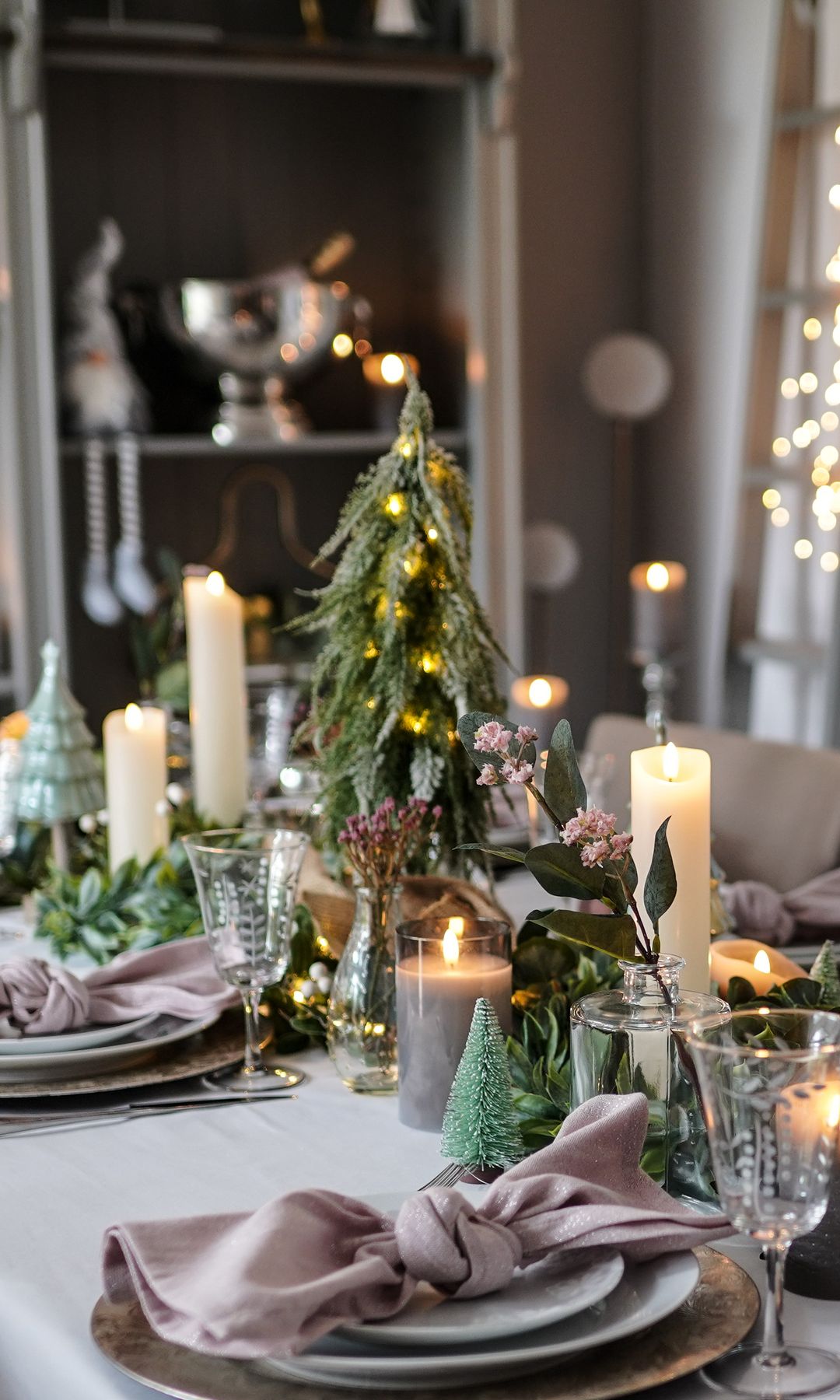 Mesa de Navidad con guirnalda en el centro, vajilla gris, velas y candelabros 