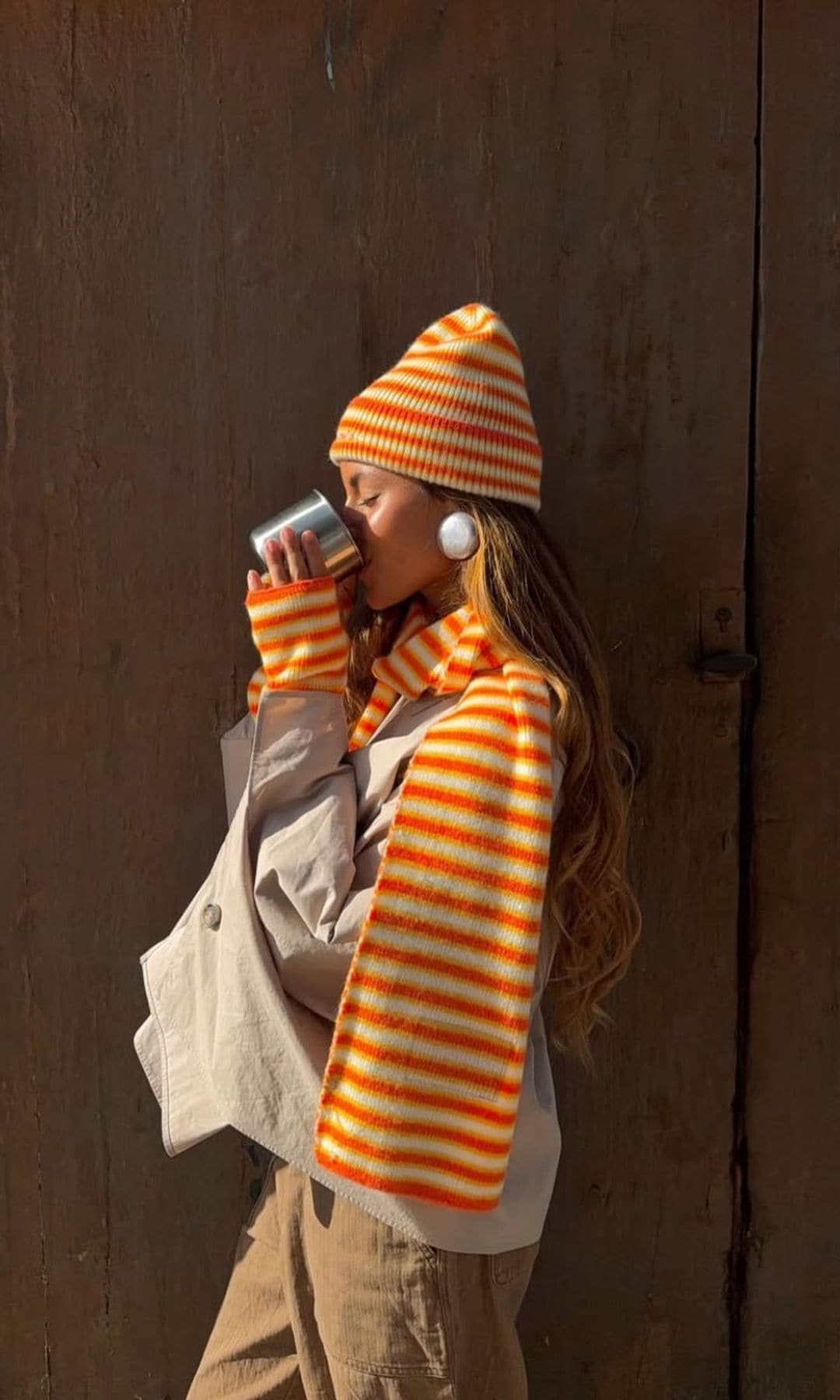 Una chica con gorro y bufanda bebiendo café