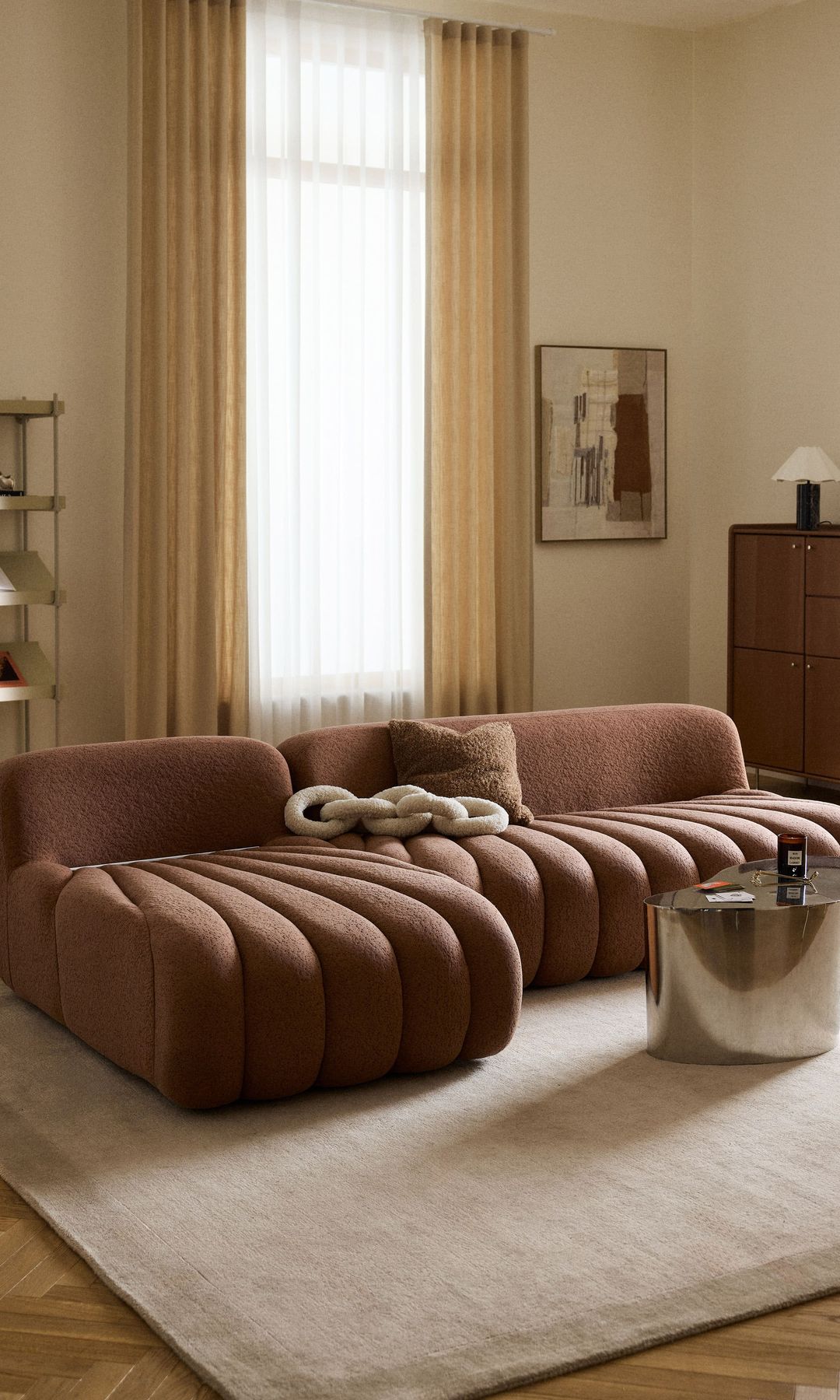 Salón con sofá marrón, cortinas, alfombra y mesa de centro 