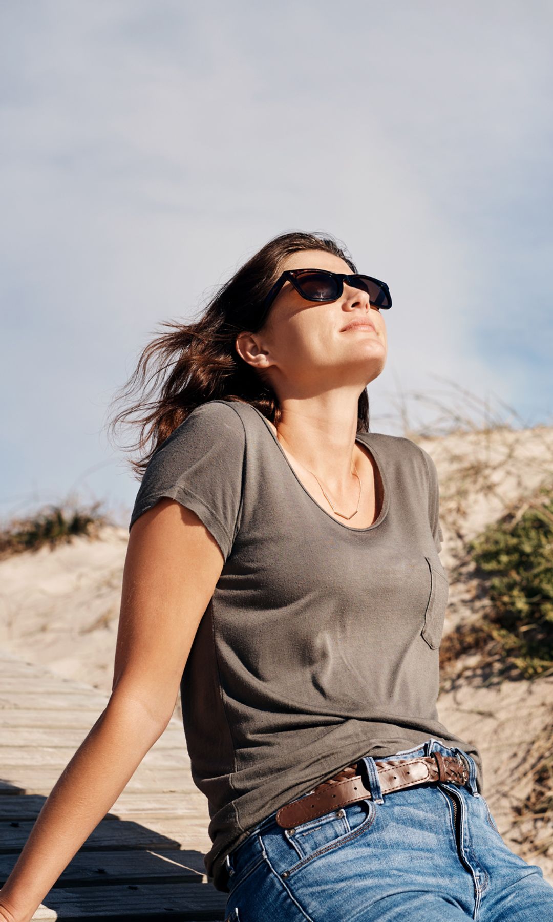 Mujer mirando el sol con gafas de sol en la playa