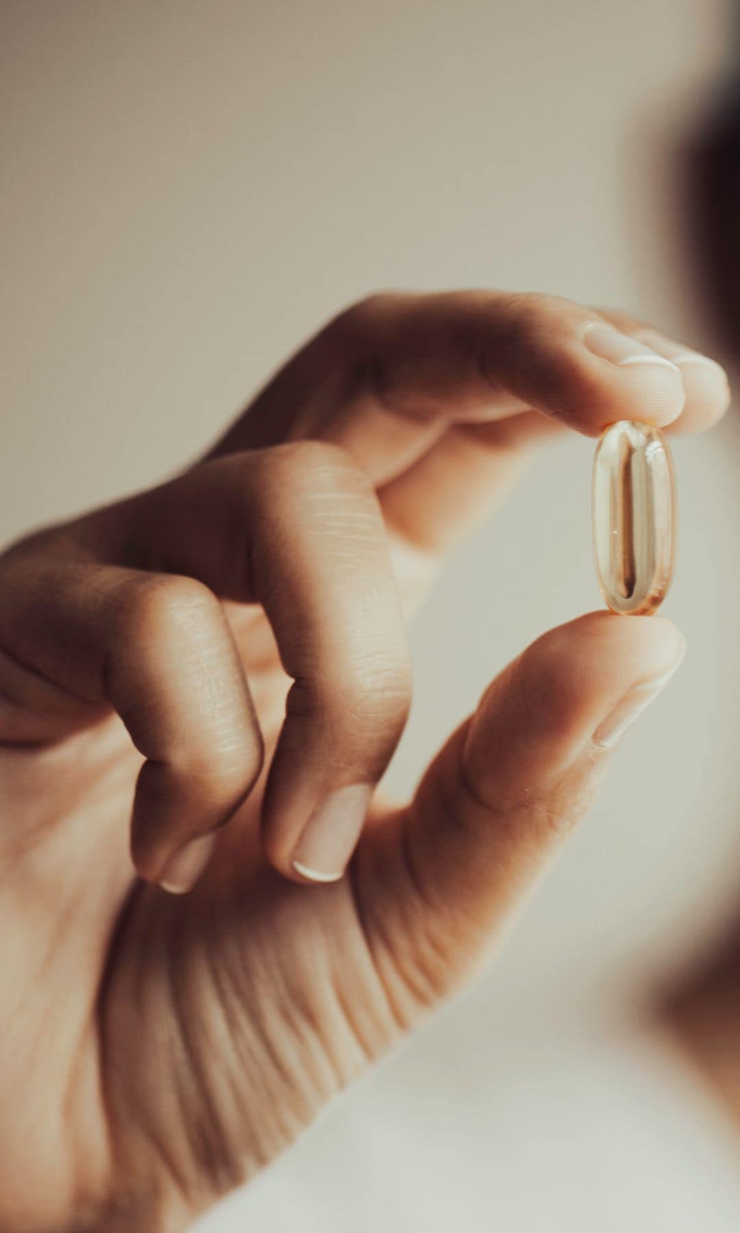 Una mujer sosteniendo una cápsula de vitaminas o complementos alimenticios