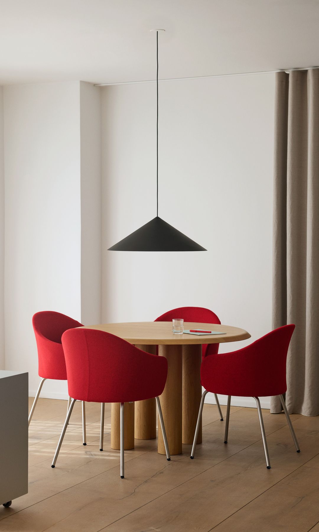 Comedor con mesa redonda de madera, sillas rojas y lámpara de techo negra