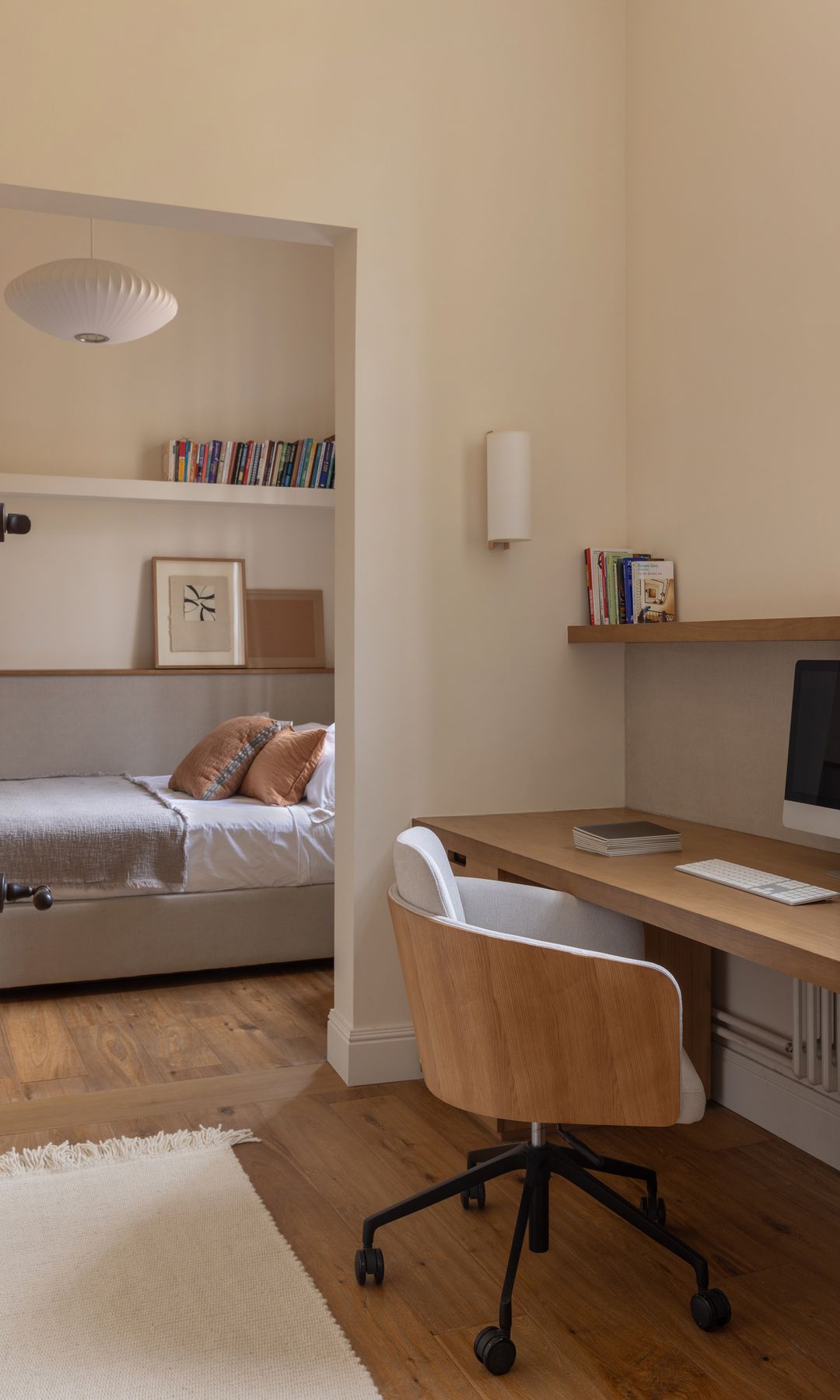 Dormitorio juvenil con zona independiente de escritorio bajo la ventana con mesa de madera, balda de madera con libros, sillas con ruedas, alfombra 
