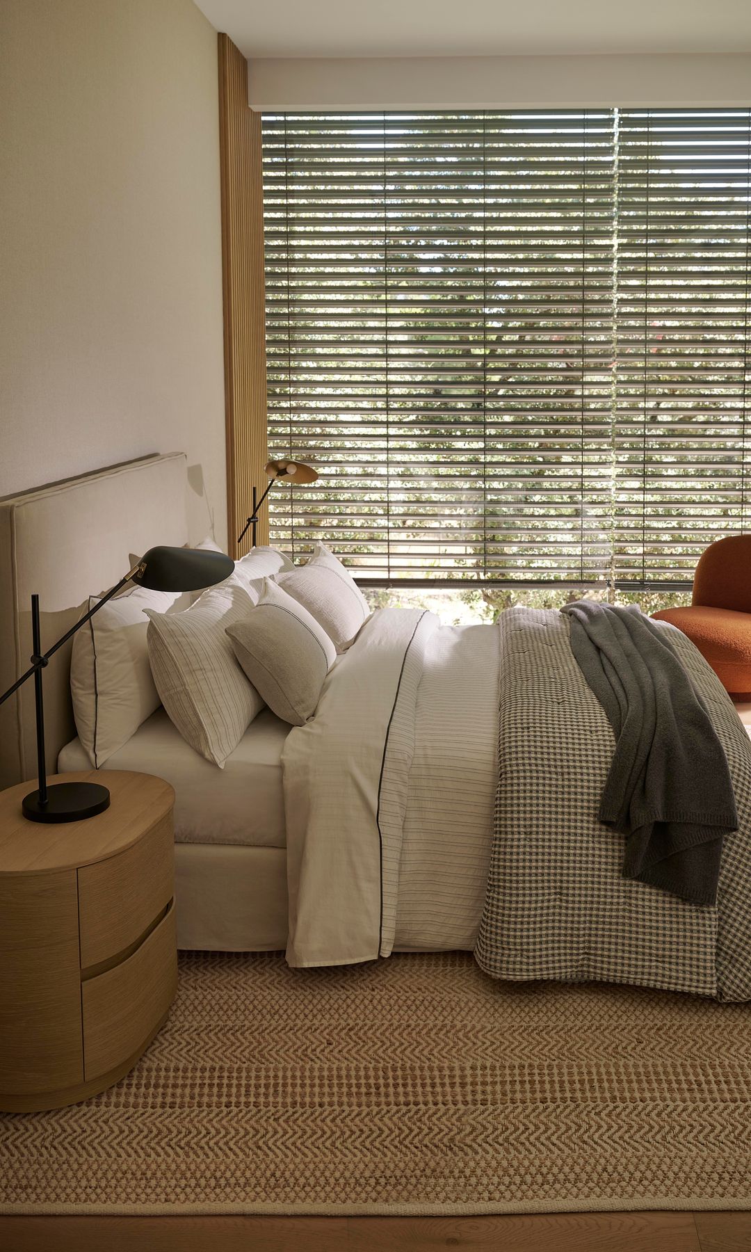 Dormitorio con persianas bajadas, cabecero tapizado, butaca, mesita de noche, lámparas de sobremesa 