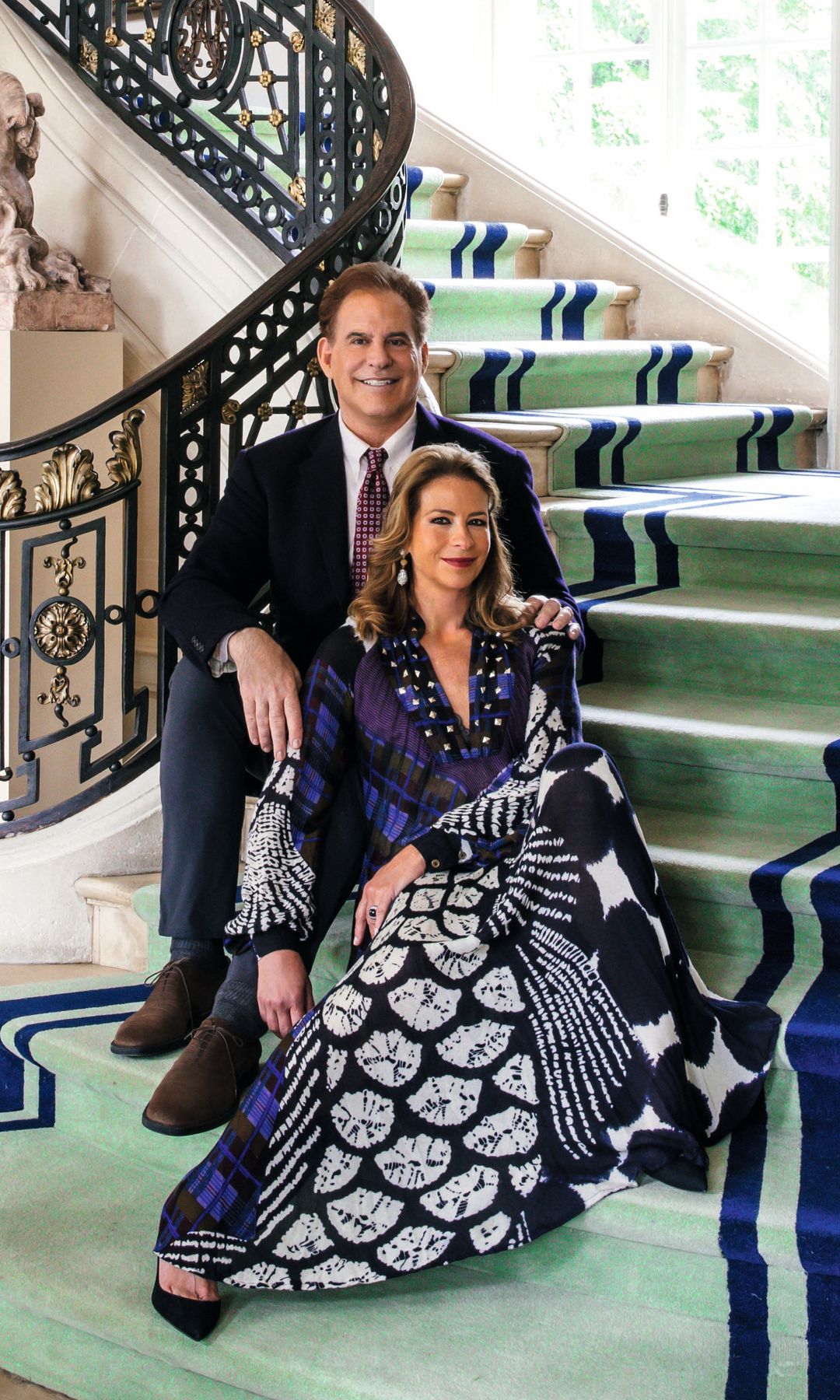 El interiorista y la baronesa en el vestíbulo, con una escalera de bronce de tres pisos, repleta de retratos de la familia de Corrigan, la realeza europea y obras de Sargent, Whistler, Boldini, Carolus-Duran, Ingres y Mapplethorpe