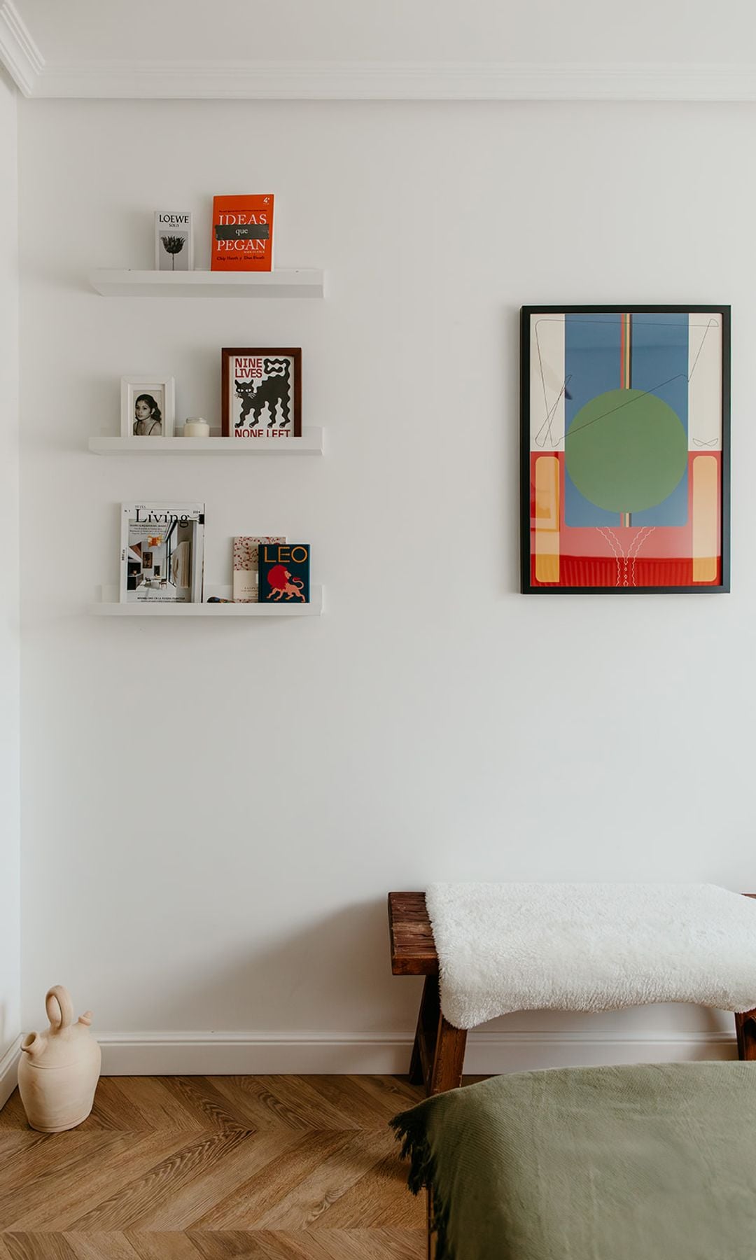 Dormitorio con banco de madera, molduras en el techo, baldas blancas, suelo de madera y cuadro