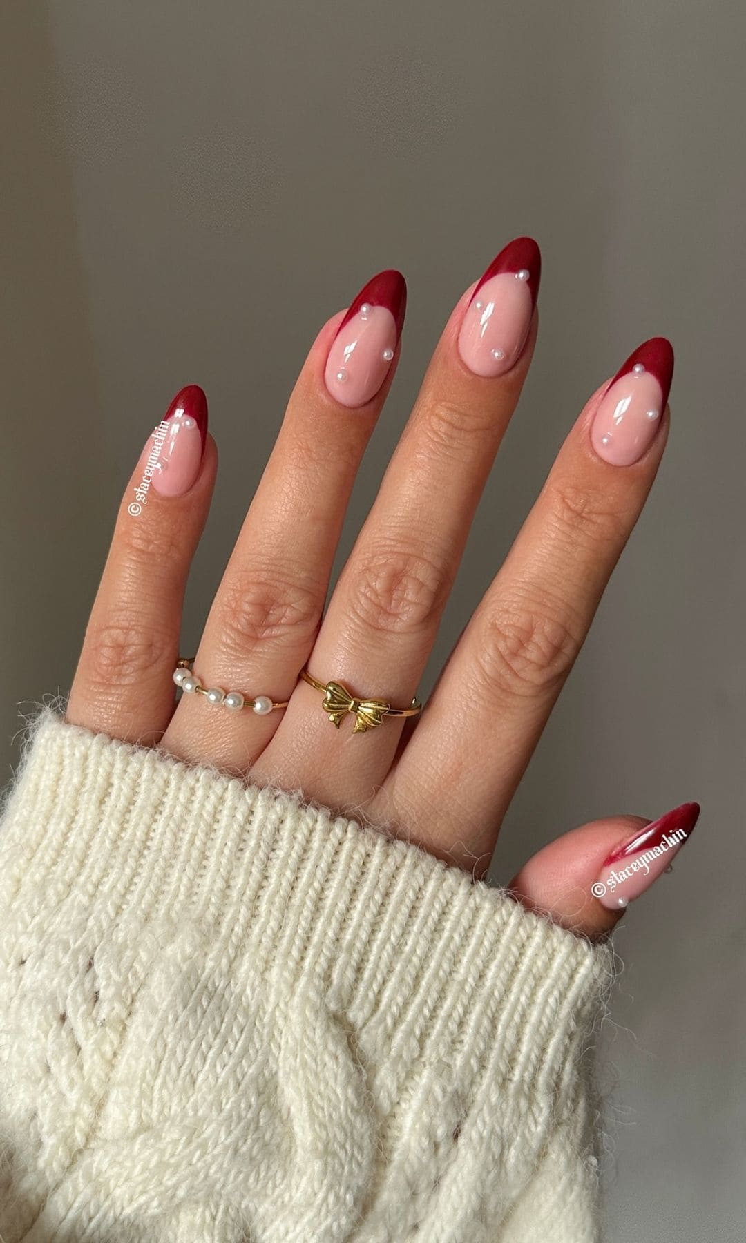 Mano con manicura francesa roja y apliques de perlas para Navidad