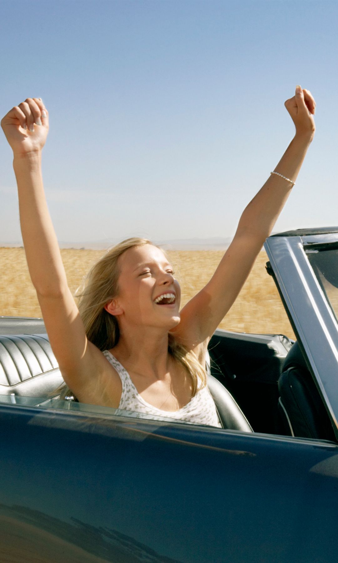 Mujeres con los brazos arriba felices en el coche