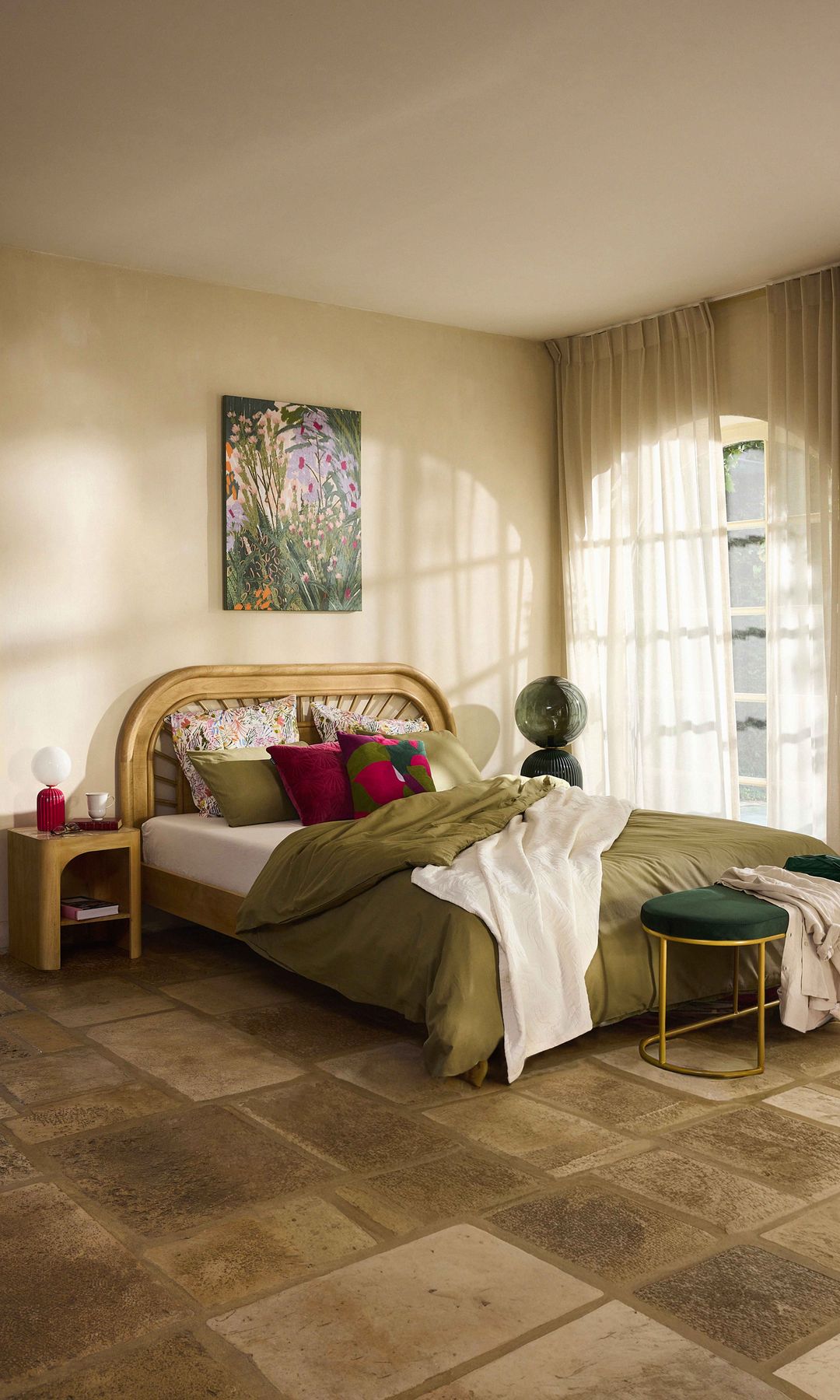 Dormitorio con cabecero de fibras vegetales, ropa de cama verde, banqueta a los pies de la cama, cuadro en la pared del cabecero 