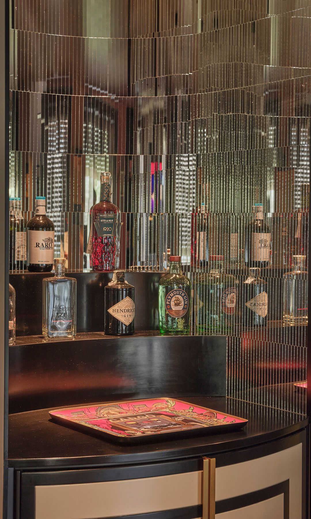 Mueble bar con paredes de espejo con baldas y botellas 