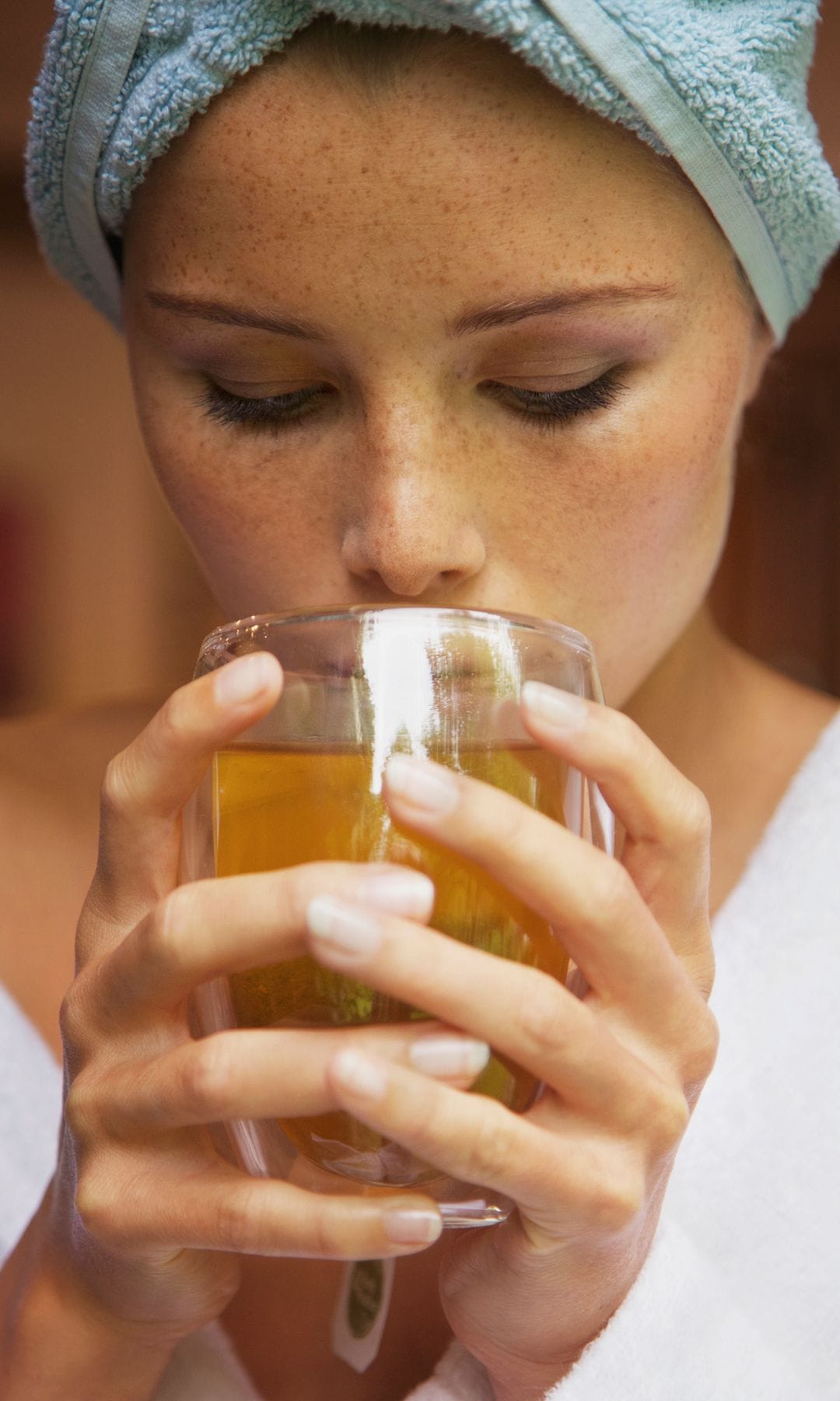 Una mujer tomándose una infusión después de la ducha para recuperarse de un resfriado