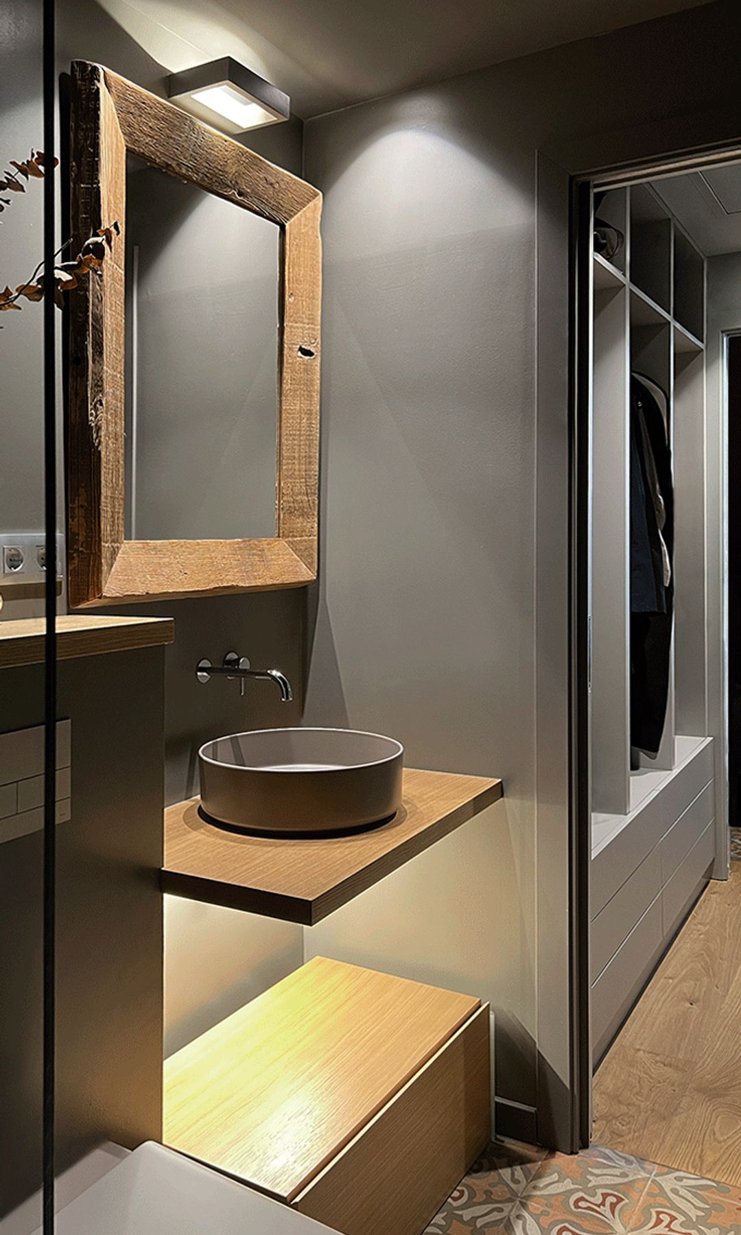 Baño con paredes grises, lavabo sobre la encimera de madera, espejo con marco de madera, sanitario, vestidor 