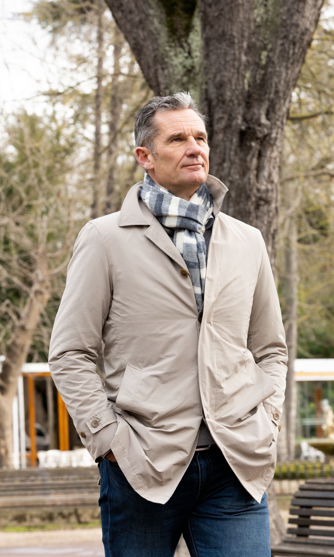 Iñaki Urdangarin, con chaqueta beige y bufanda a cuadros, en un parque.
