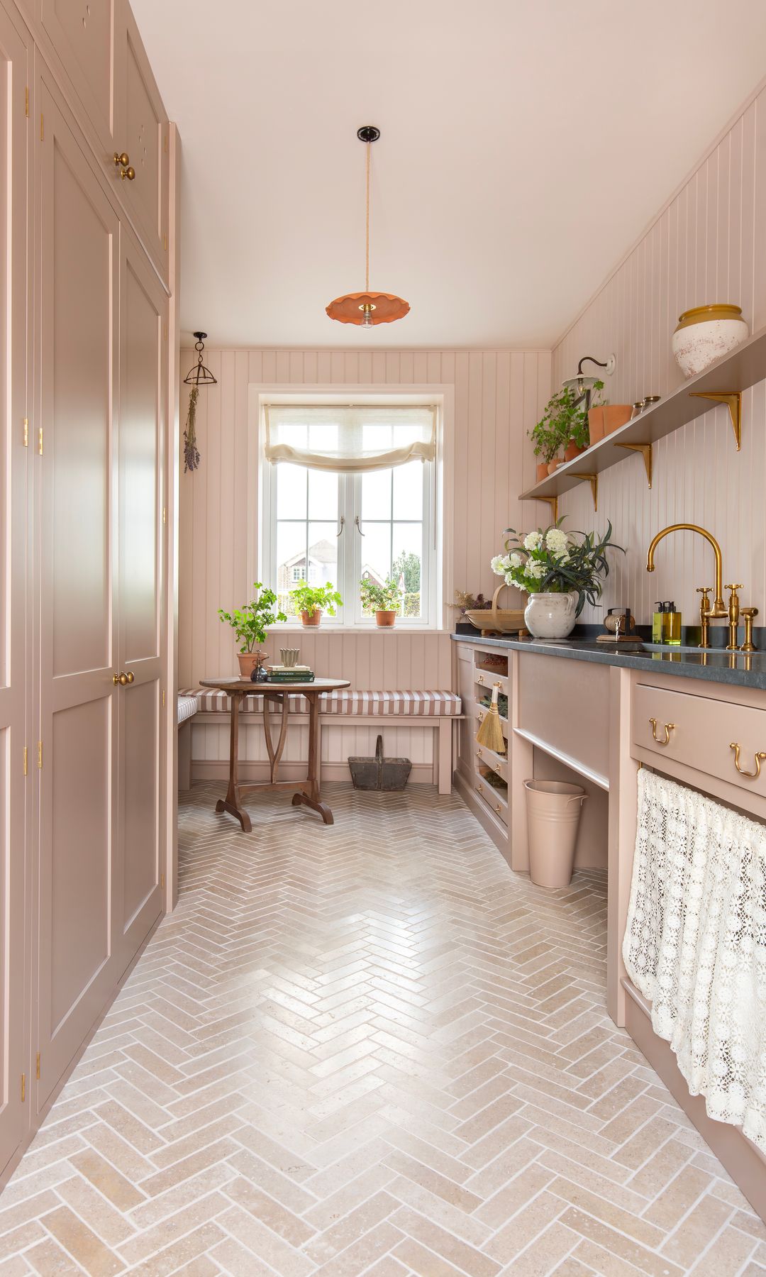 Cocina clásica, estrecha y alargada, con muebles de color beige, cortinilla bajo la encimera, zona de office bajo la ventana