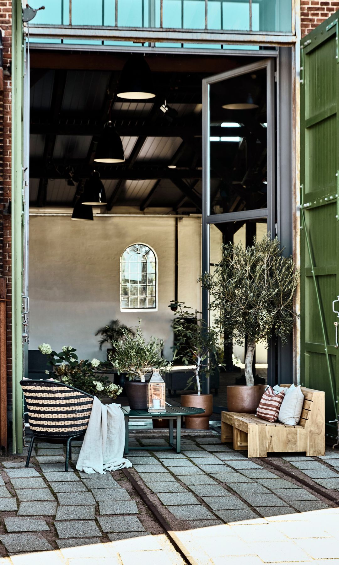 Salón exterior con muebles de palets, conectado con el interior