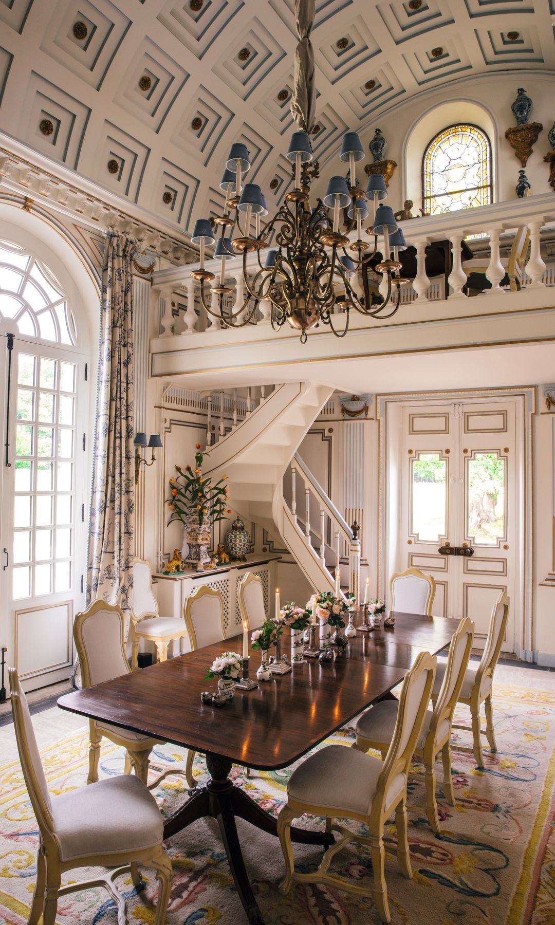 Comedor con mesa larga, sillas, candelabro y escalera