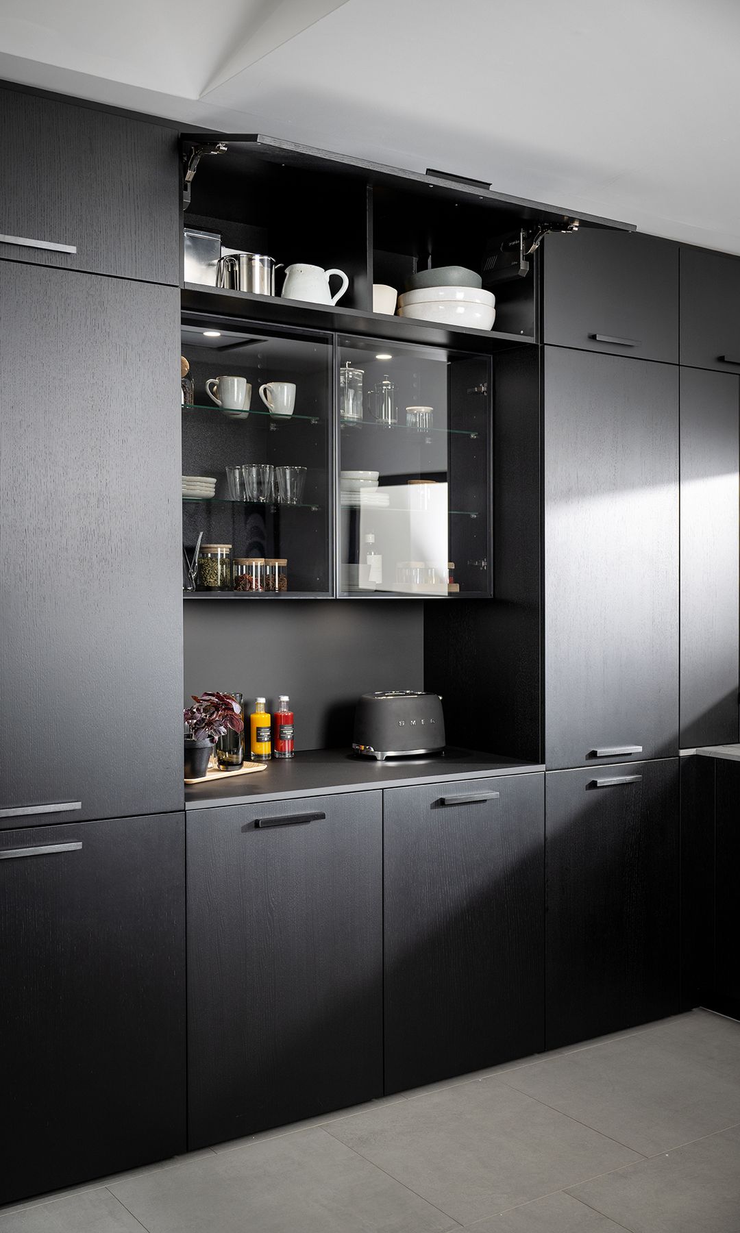 Cocina negra con vitrina y desayunador con tostadora y tazas
