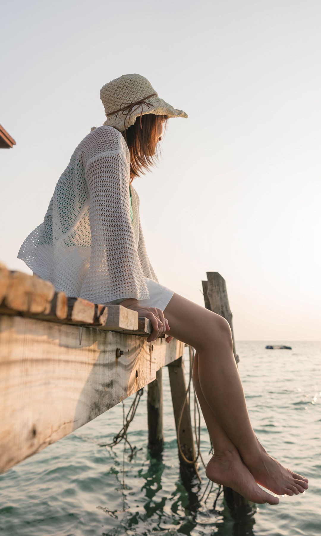 mujer sentada en el muelle mirando al horizonte del mar