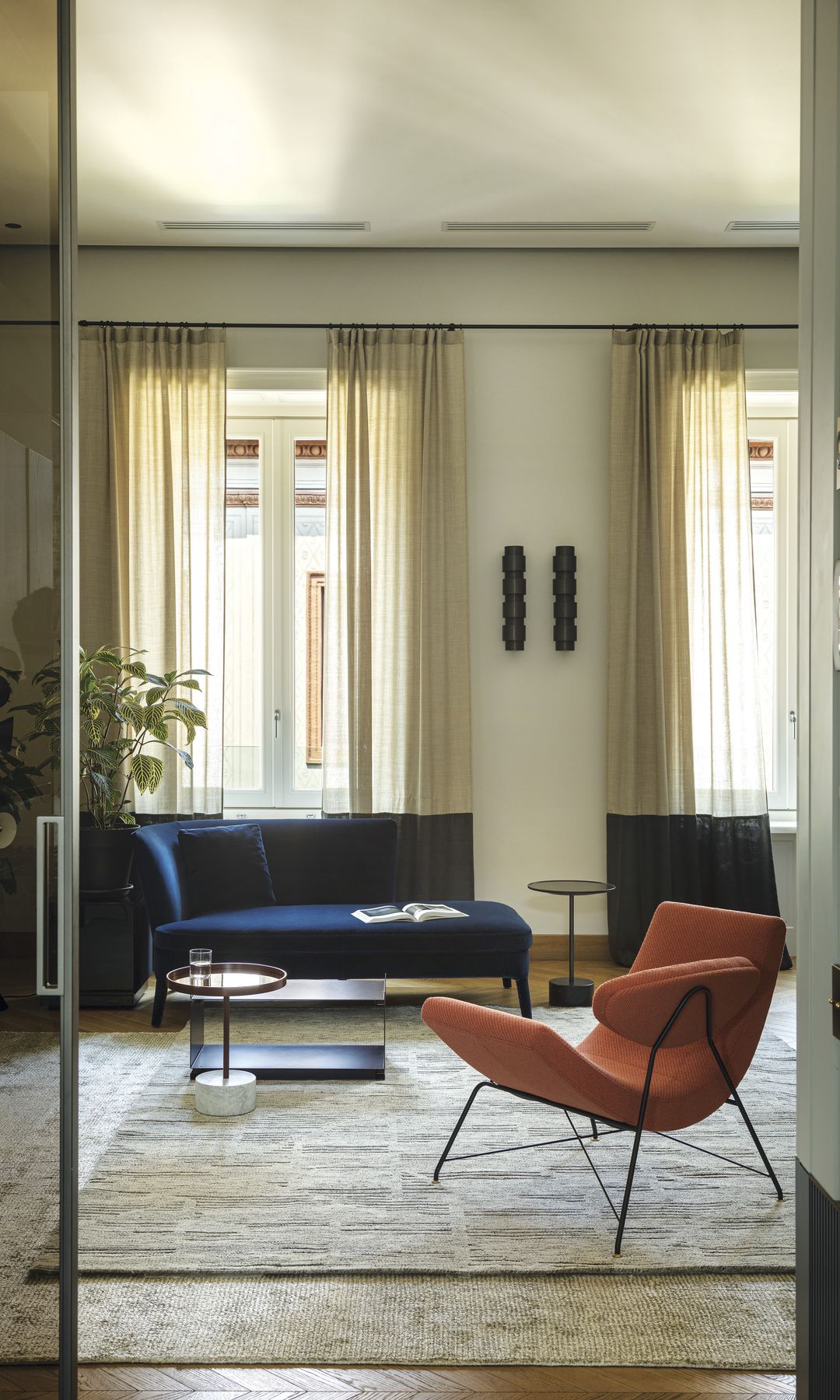 Salón con alfombra, sofá azul, butaca marrón, mesa de centro negra