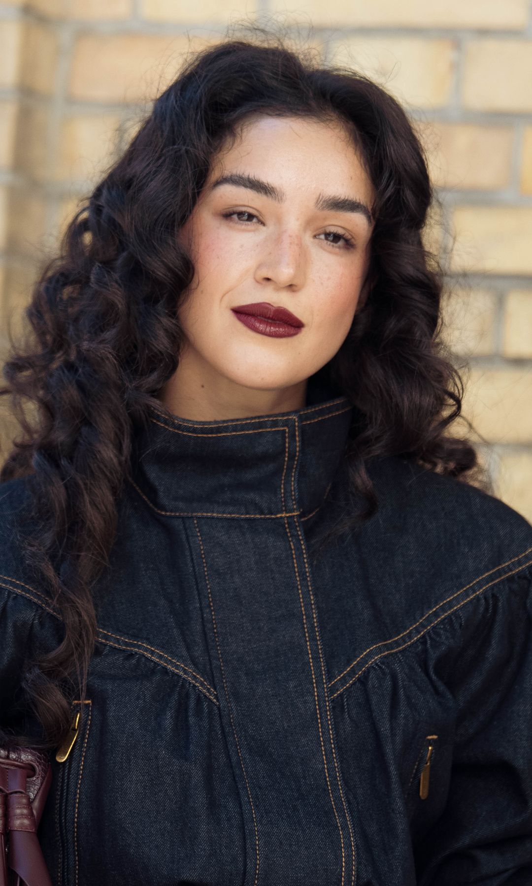 Muejr con cabello rizado y maquillaje con labios burdeos