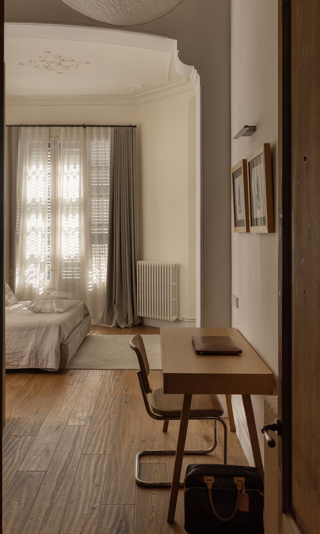 Dormitorio con zona de escritorio, ventana con personas, cortinas y visillos 