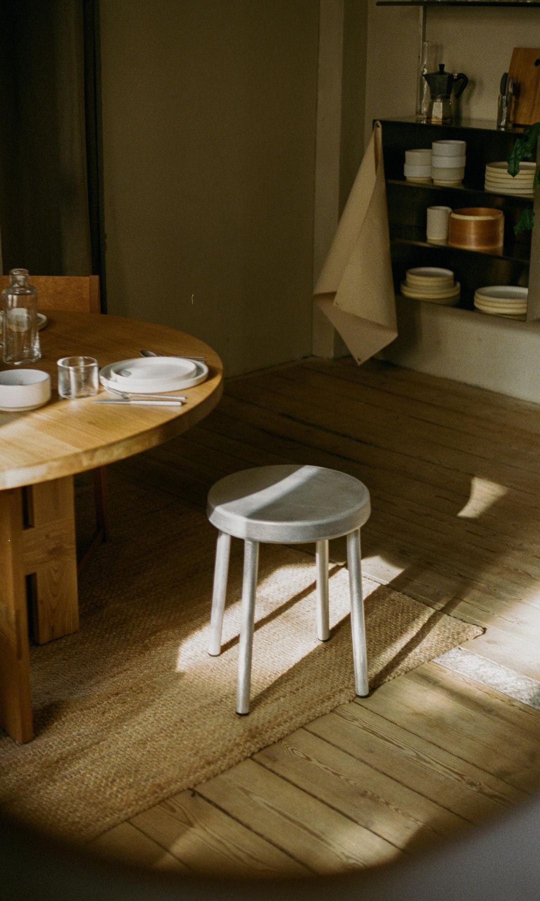Comedor con mesa de madera, alfombra de fibras vegetales y taburete metálico