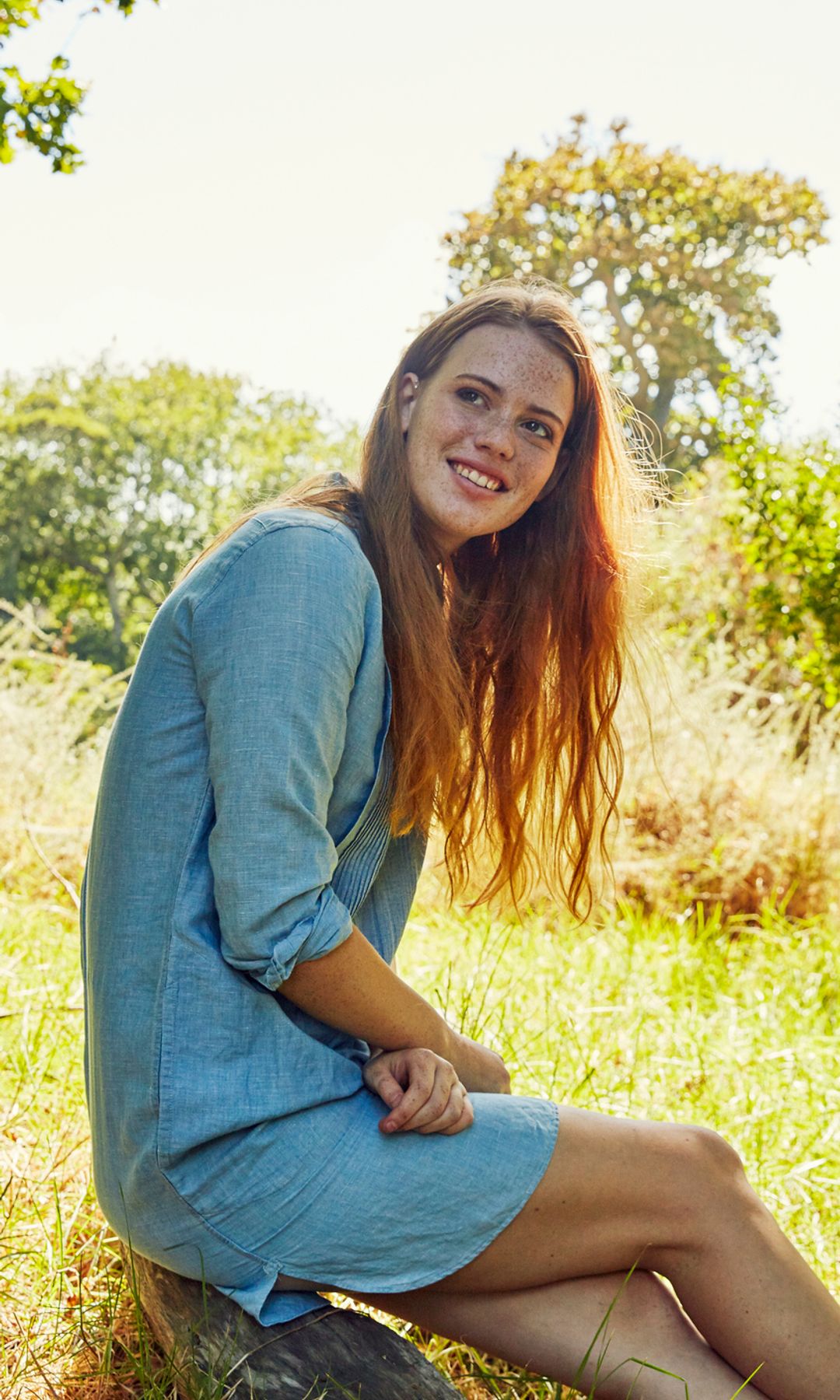 Retrato de una mujer sentada en el campo rodeada de árboles
