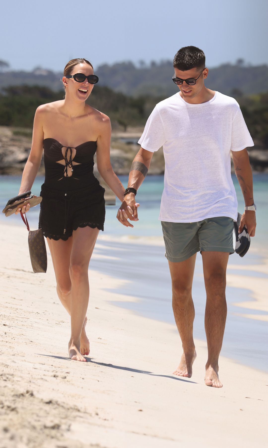 La pareja pasea sonriente por la orilla en una playa de Formentera